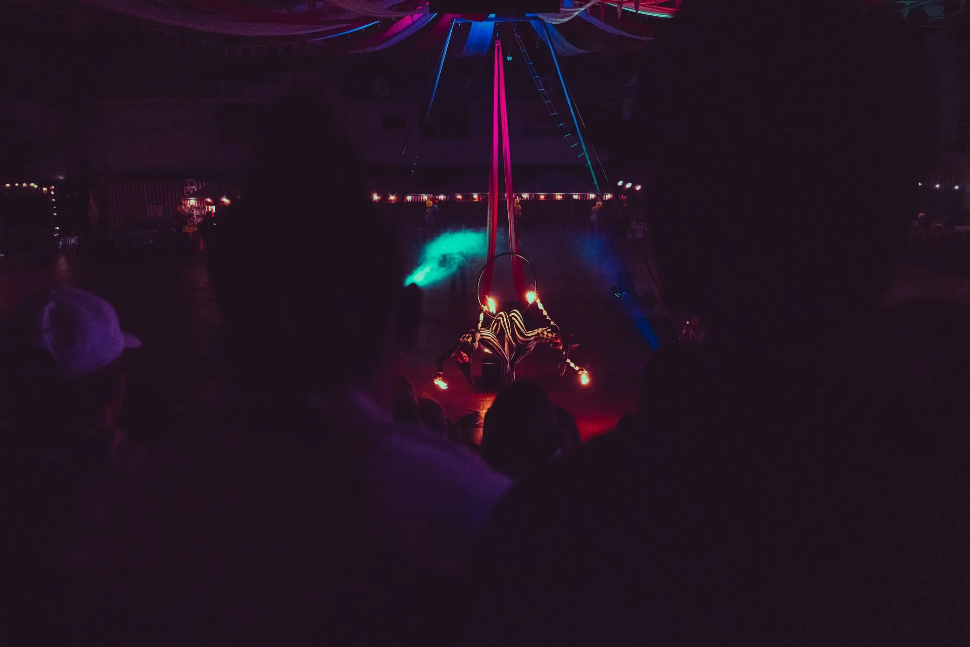 A group of people are standing in front of a stage in a dark room.