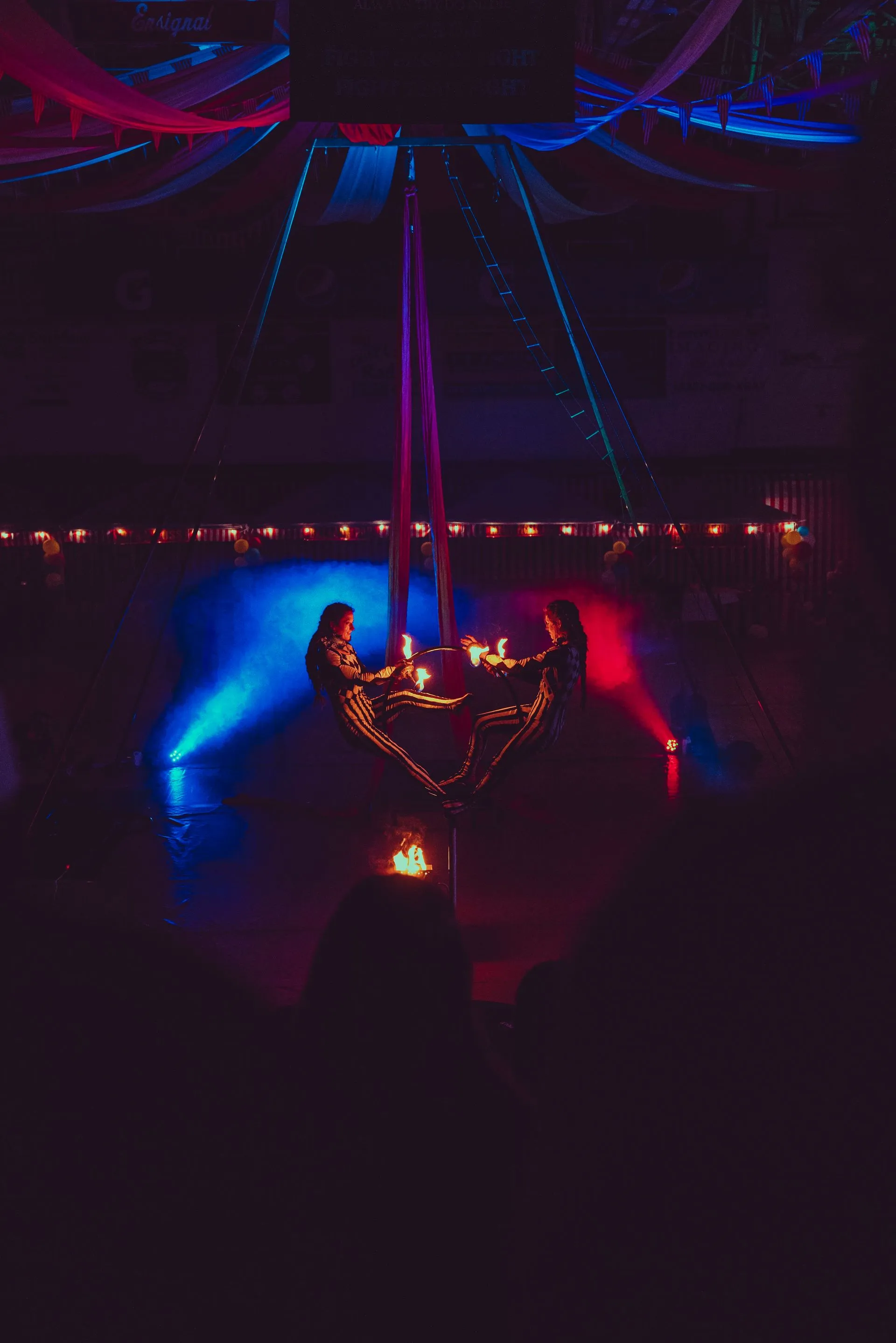 Two women are sitting at a table with candles in a dark room.