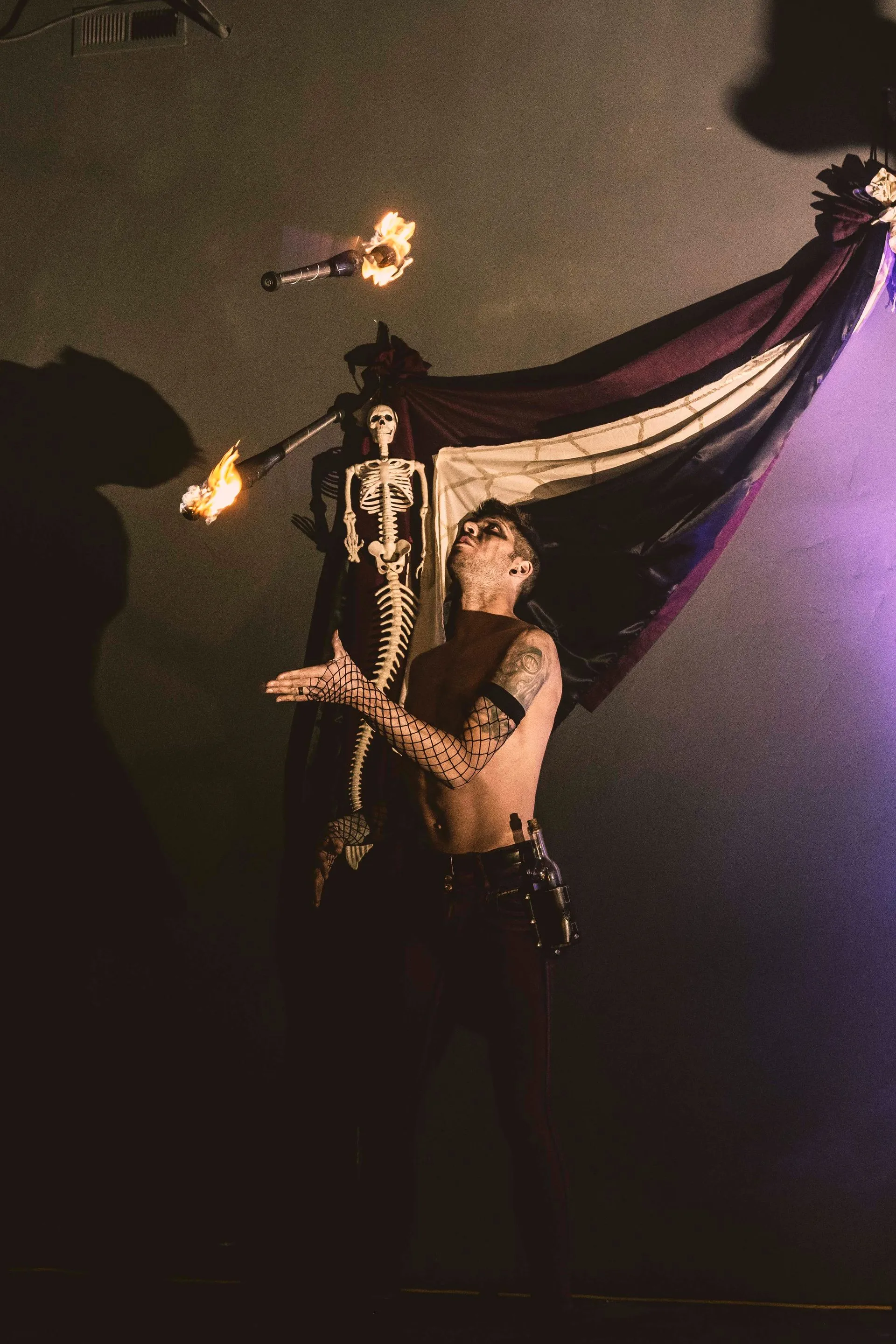 A man is juggling fire with a skeleton in the background.