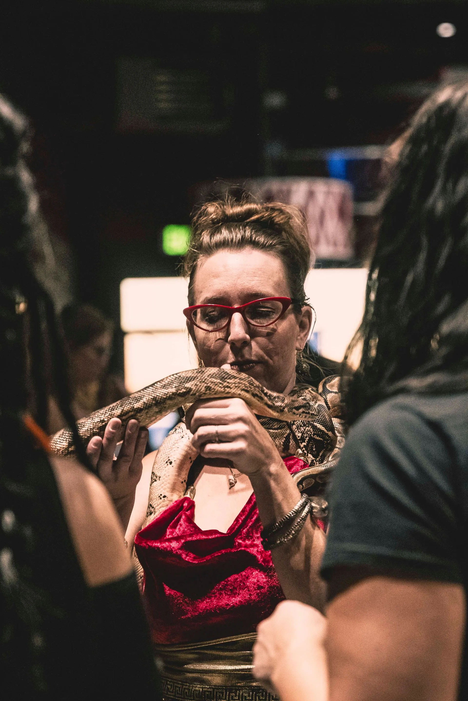A woman is holding a snake in her hands in a crowd of people.