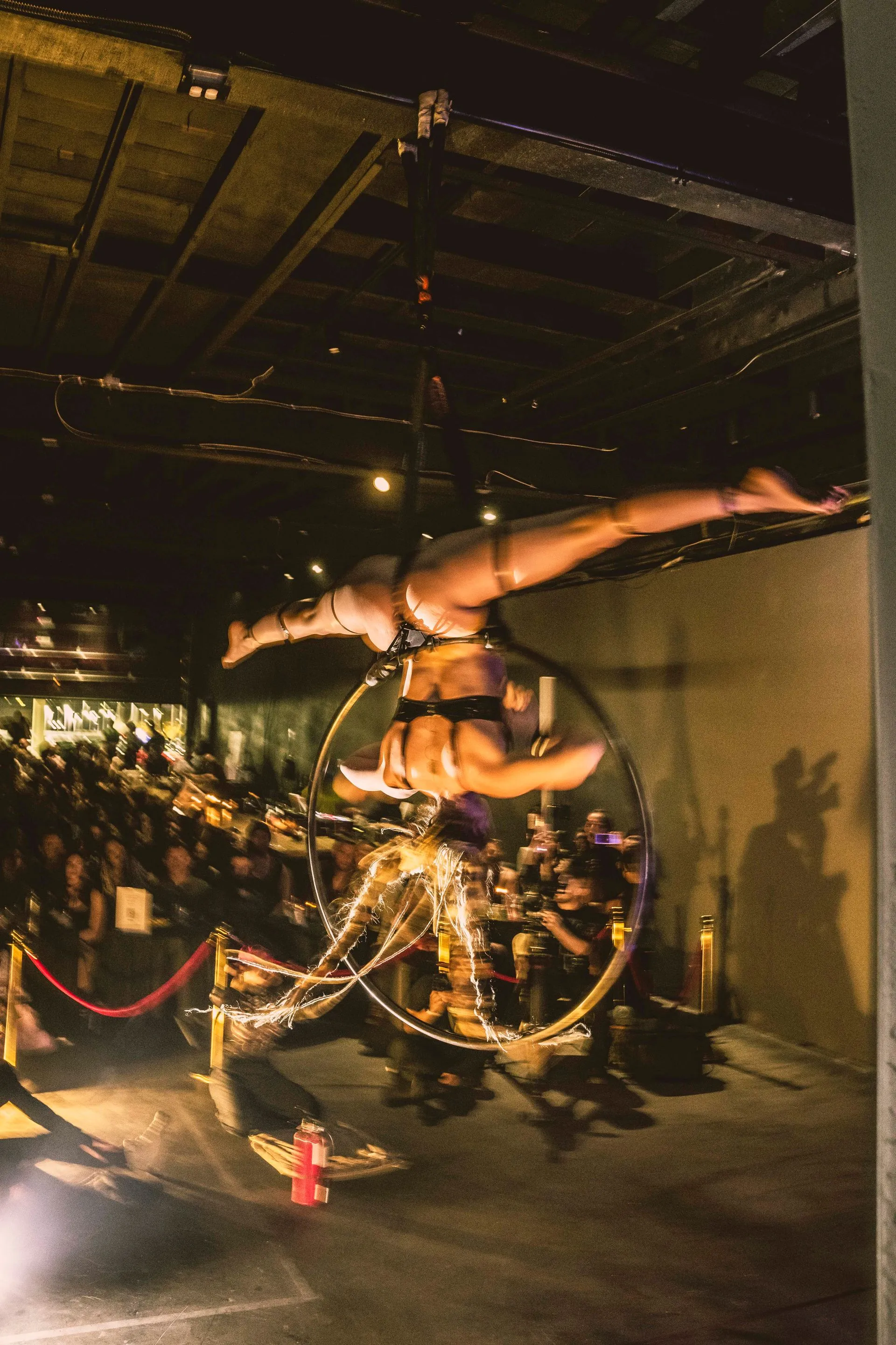A woman is hanging upside down in an aerial hoop.