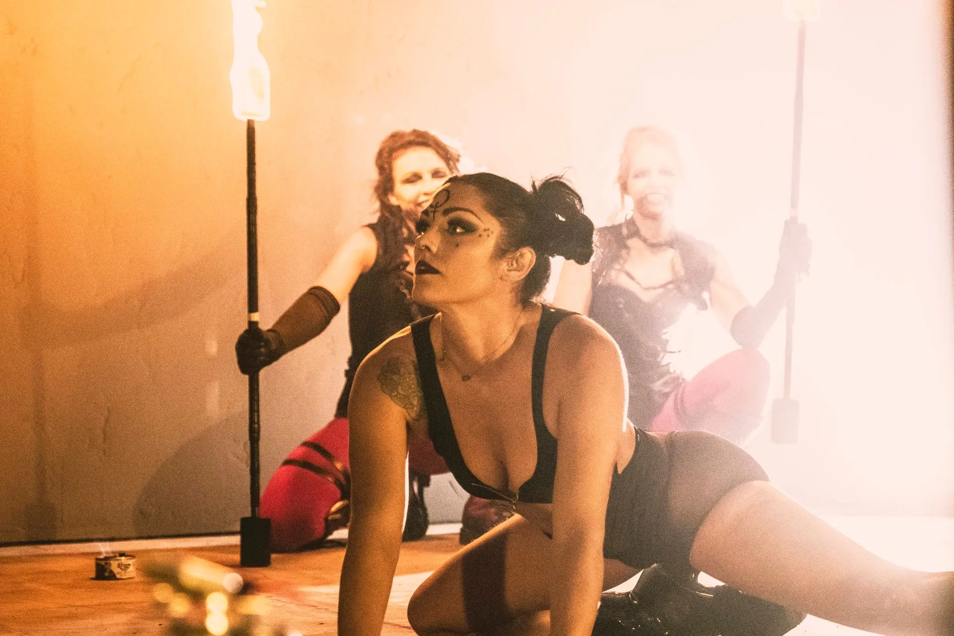 A woman is kneeling on the floor holding a torch while another woman stands behind her.
