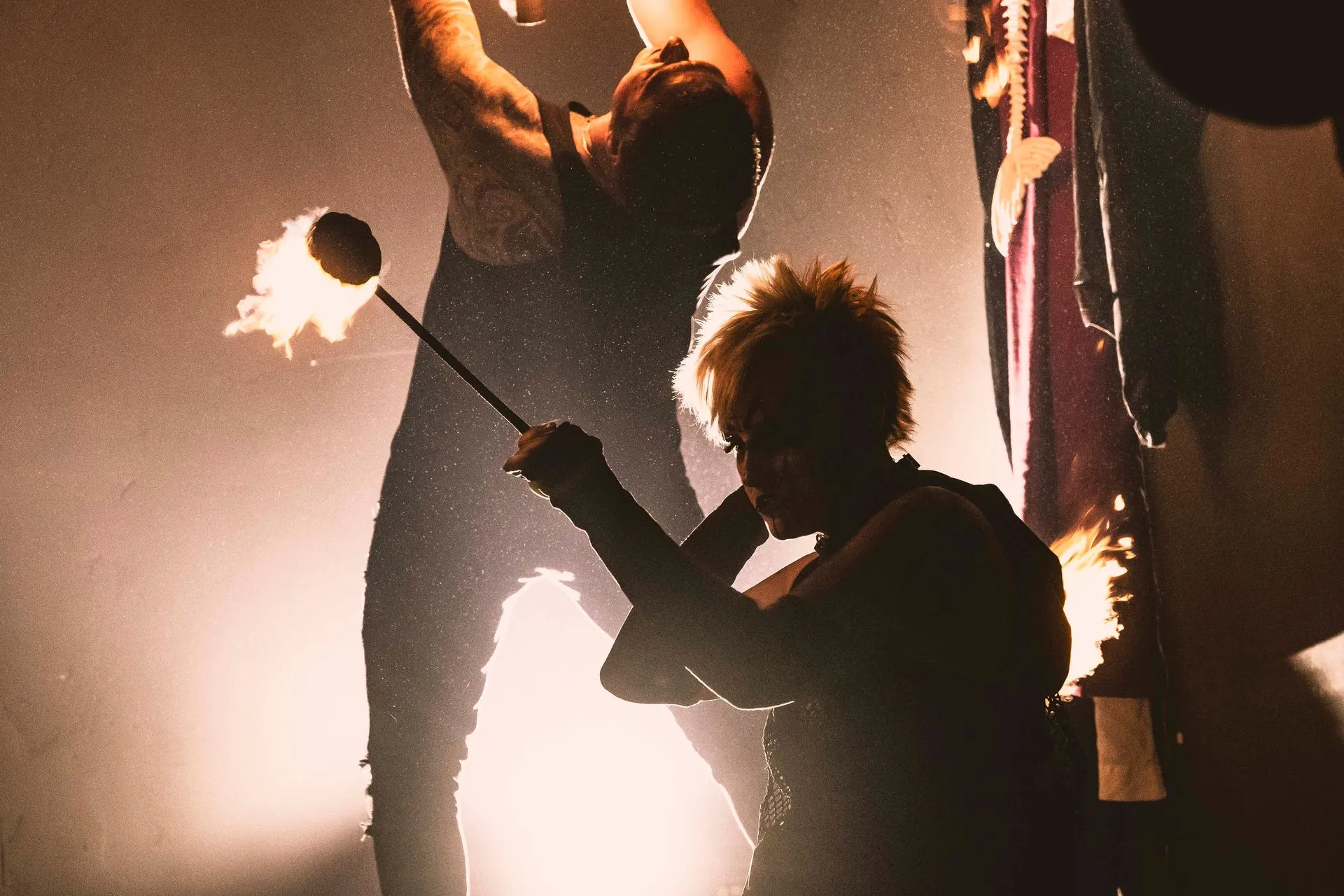 A man is holding a stick with flames on it while a woman looks on.
