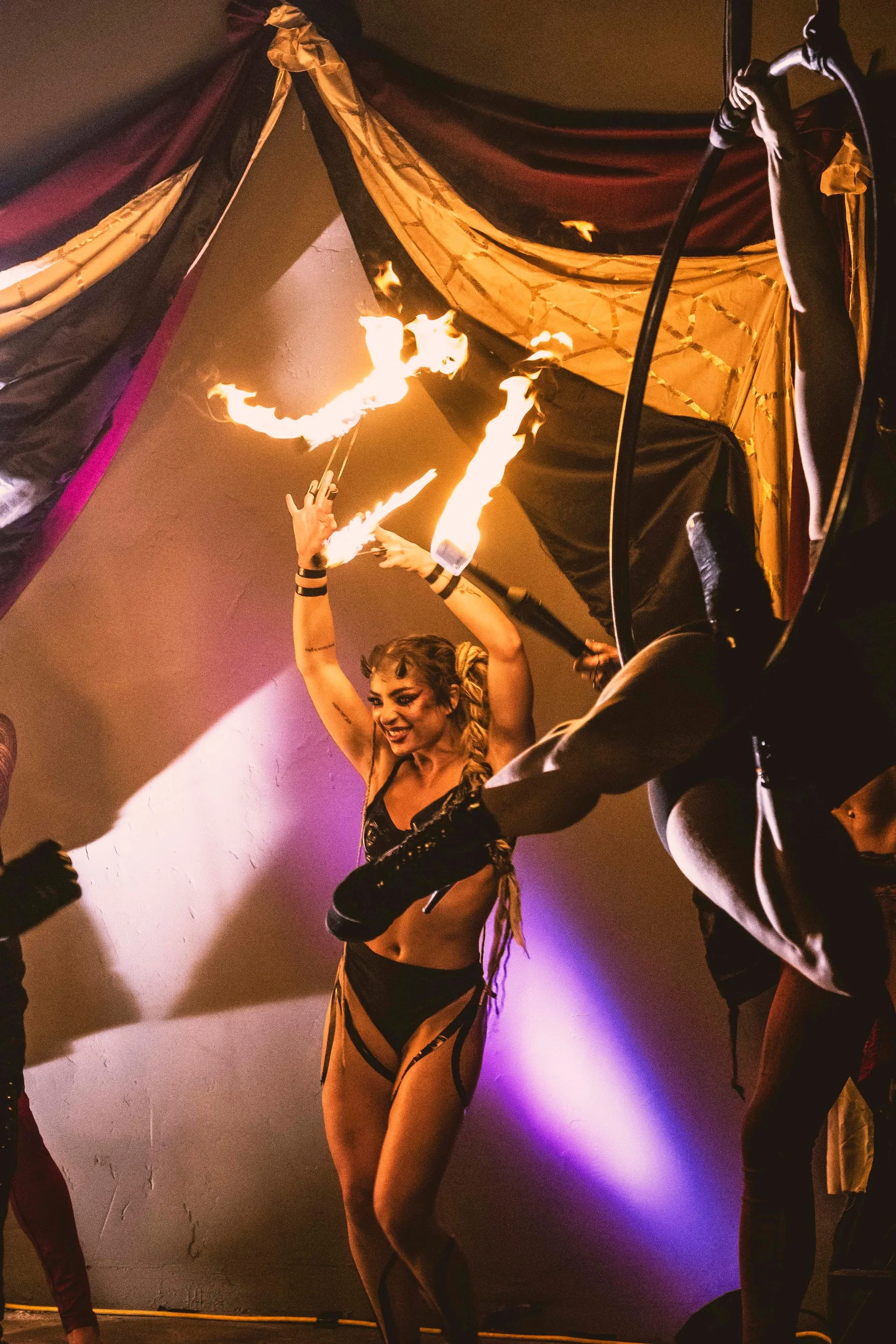 A woman is holding a stick of fire while dancing on a stage.