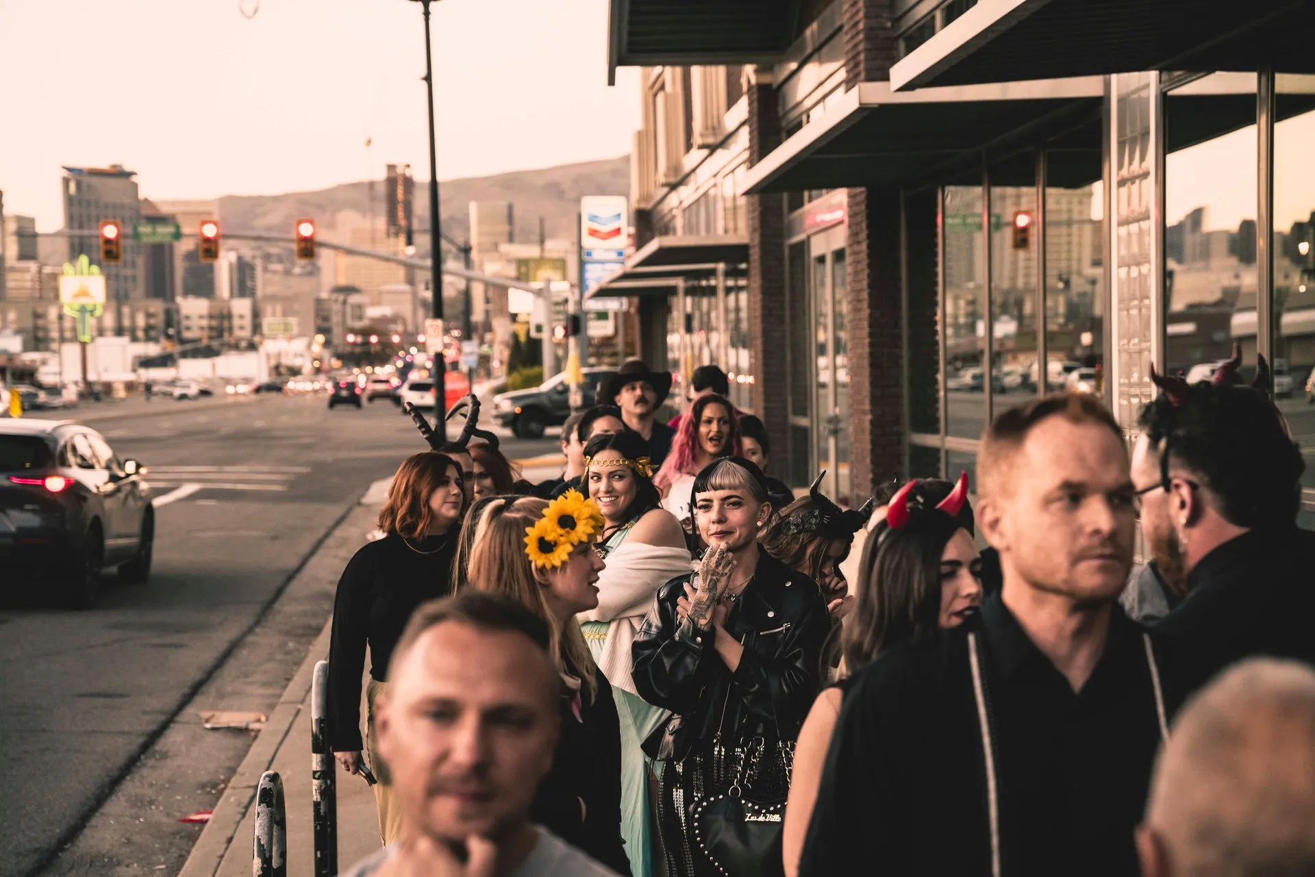 A group of people are standing in a line on the sidewalk.