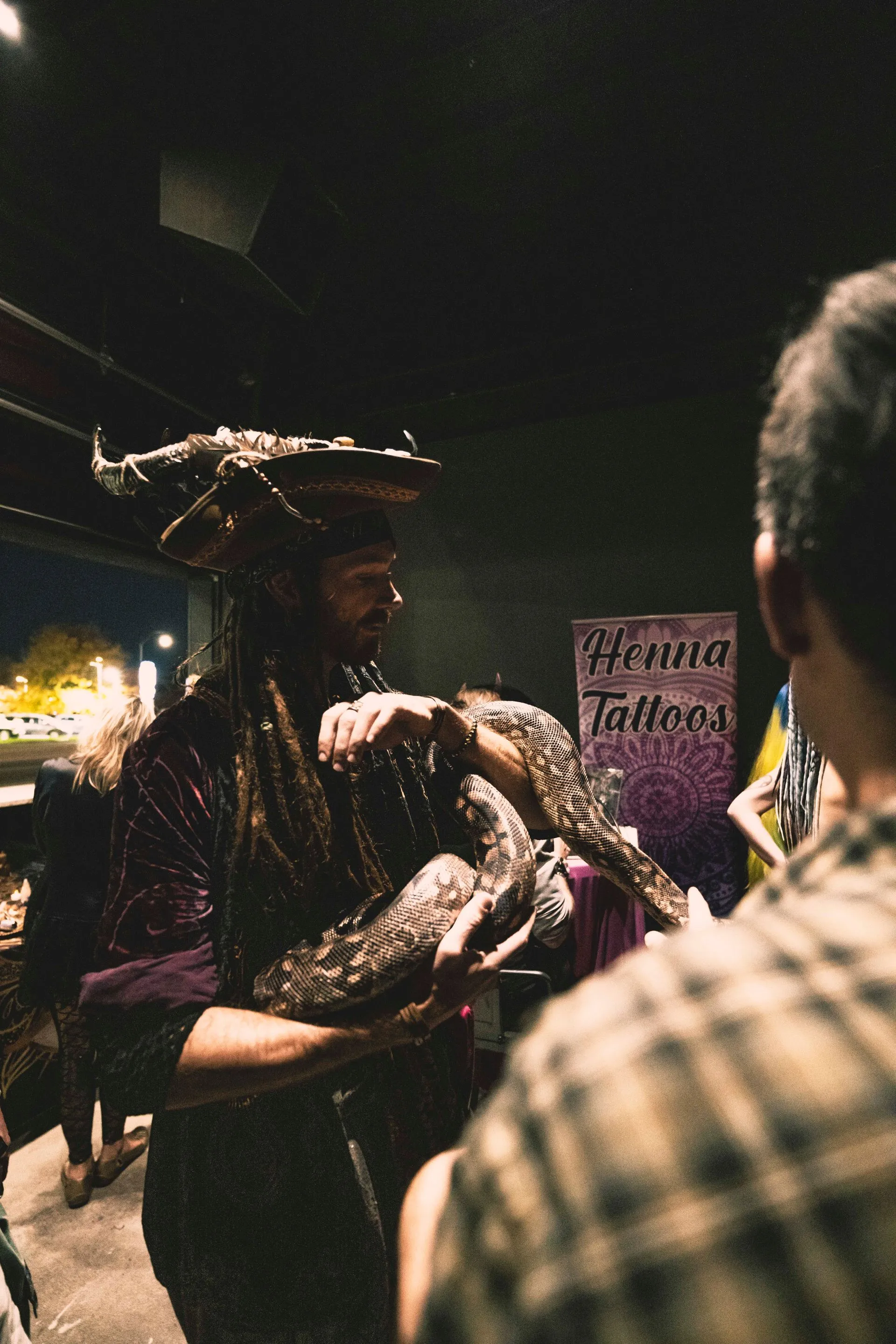 A man in a pirate costume is holding a large snake in his hands.