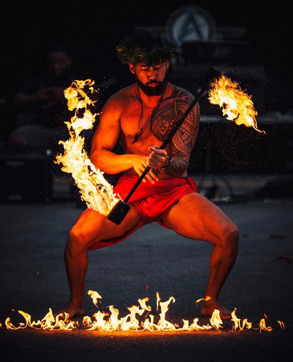 A shirtless man is holding a stick with flames coming out of it