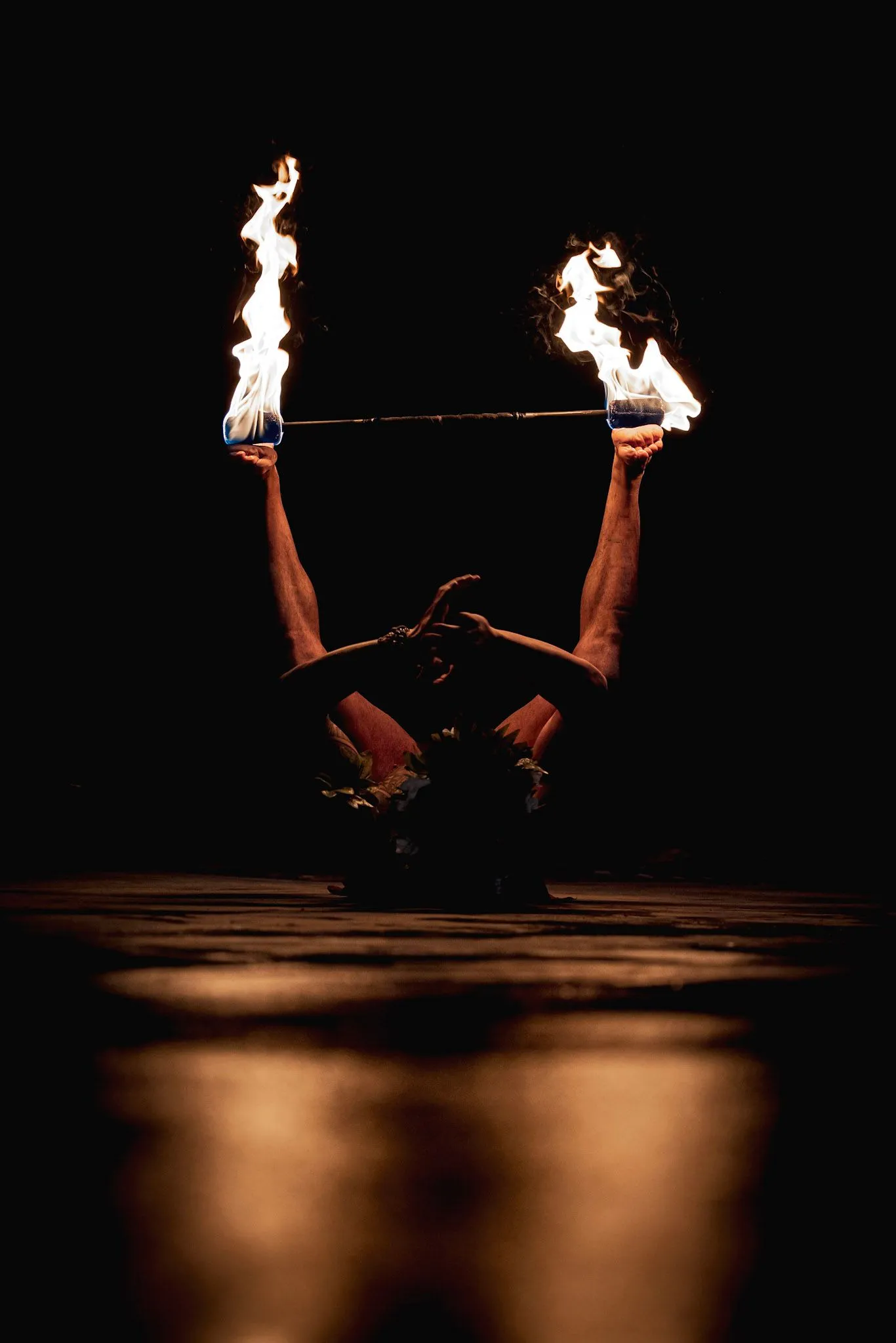 A person is holding two fire torches in their hands in the dark.