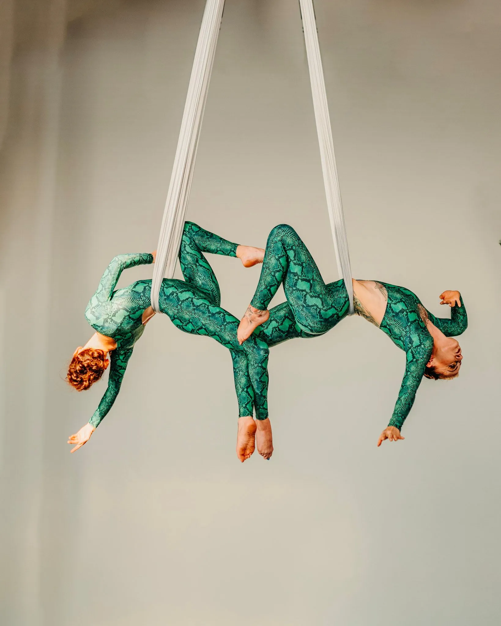 Two women are doing aerial acrobatics on a rope.