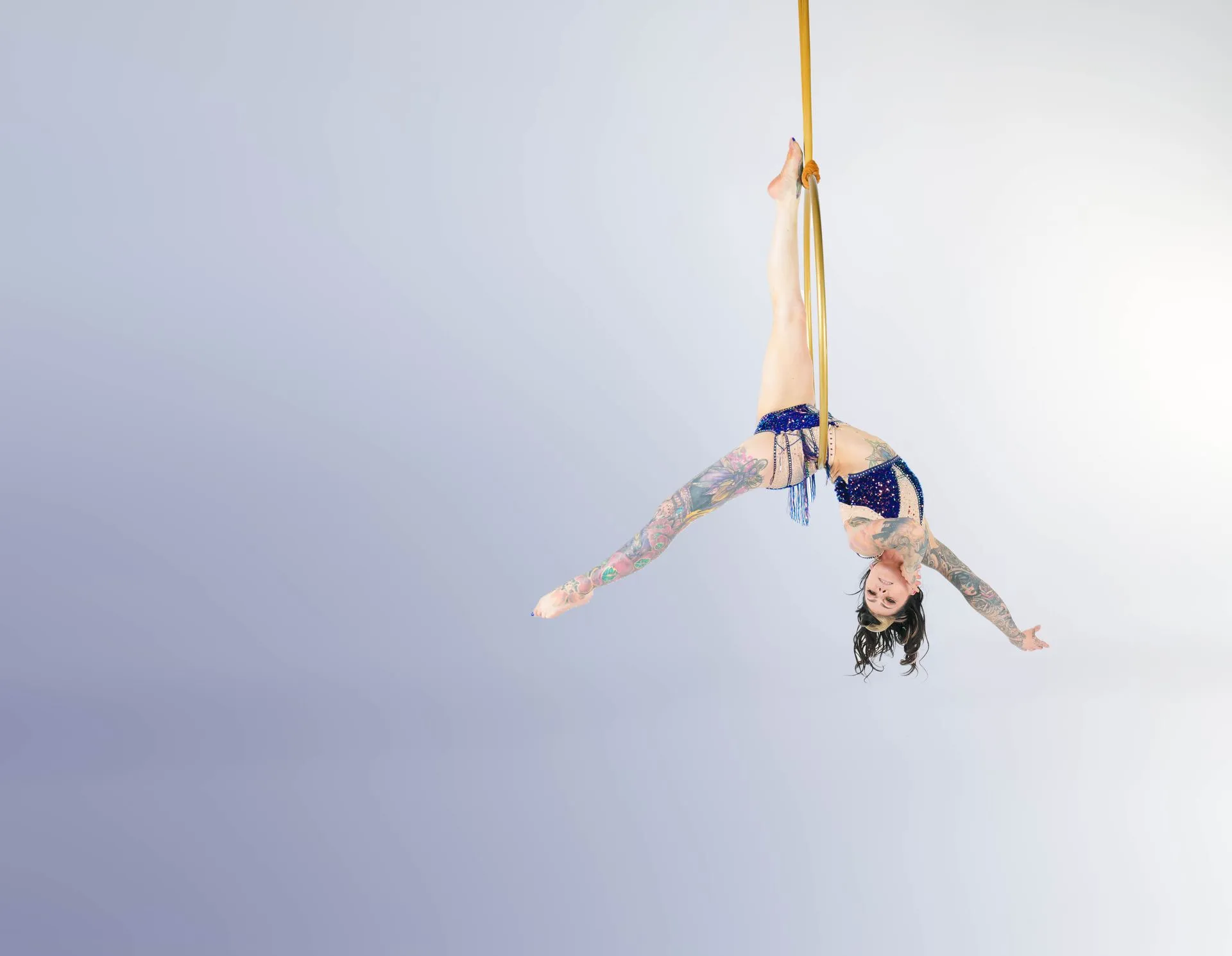 A woman is doing aerial acrobatics on a pole.