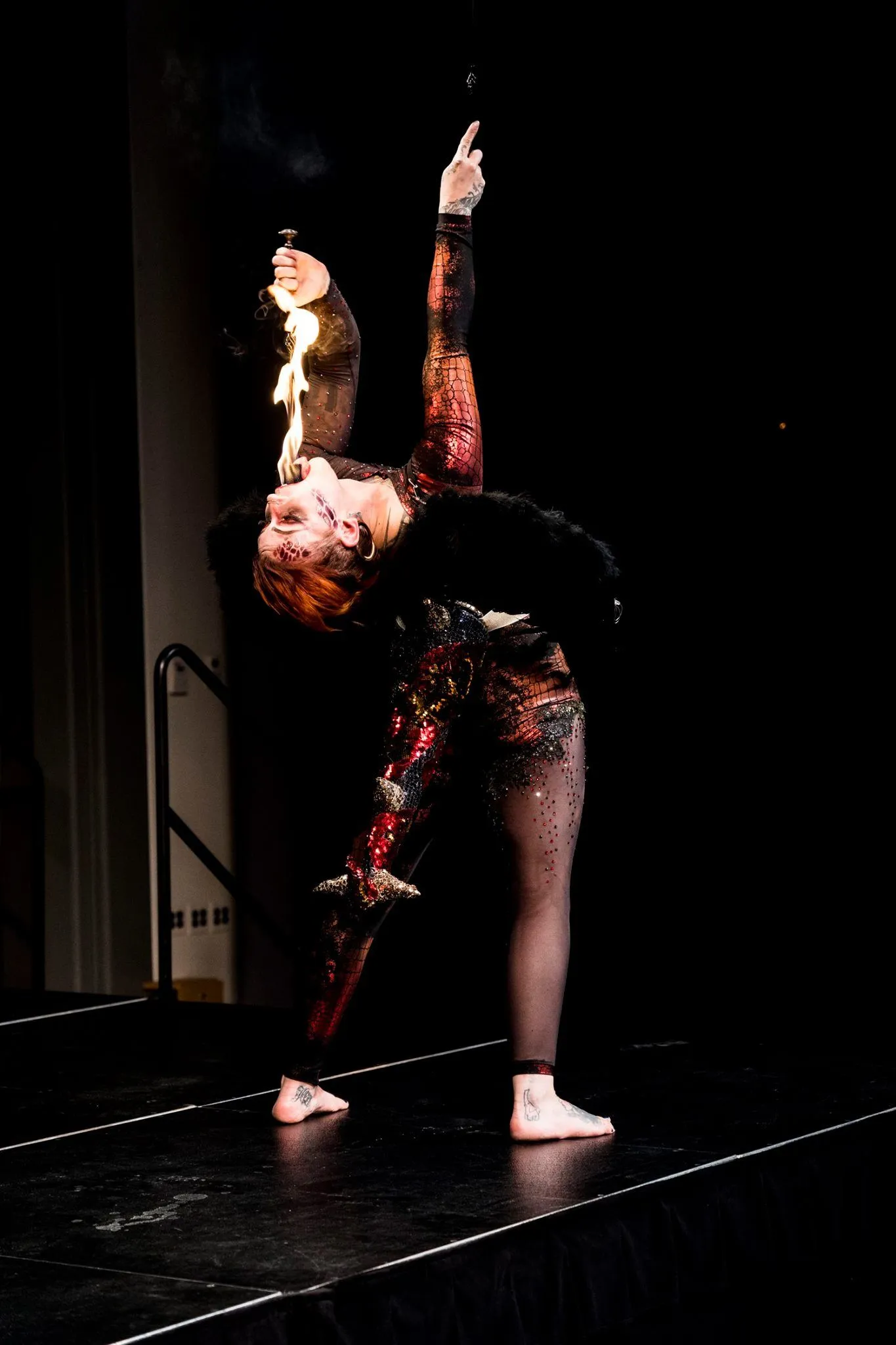 A woman in a colorful costume is doing a handstand on a stage.