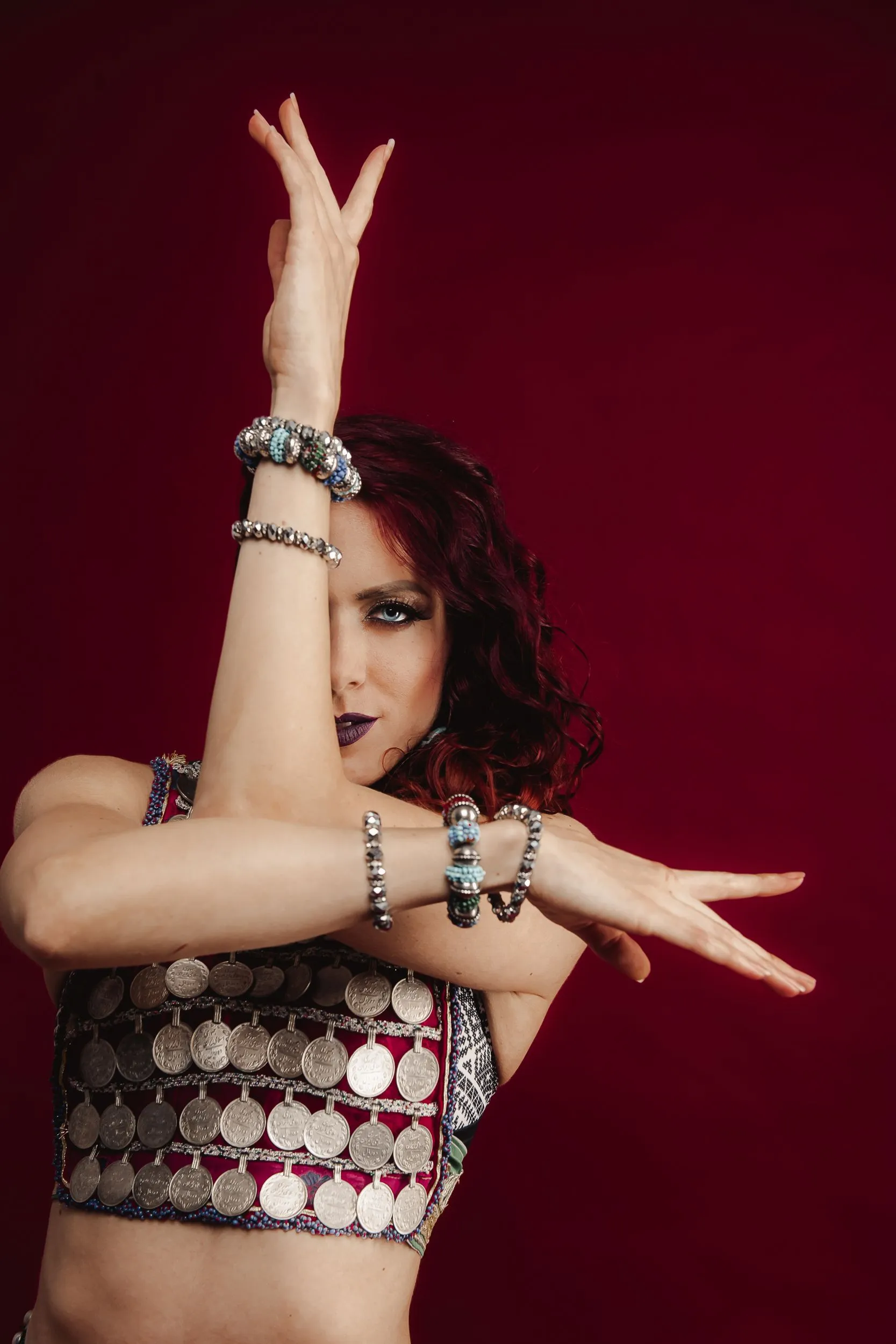 A belly dancer is dancing with her hands in the air.