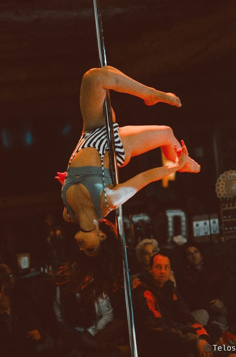 A woman is doing a handstand on a pole in front of a crowd.