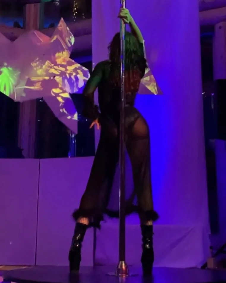 A woman is standing on a pole in a dark room