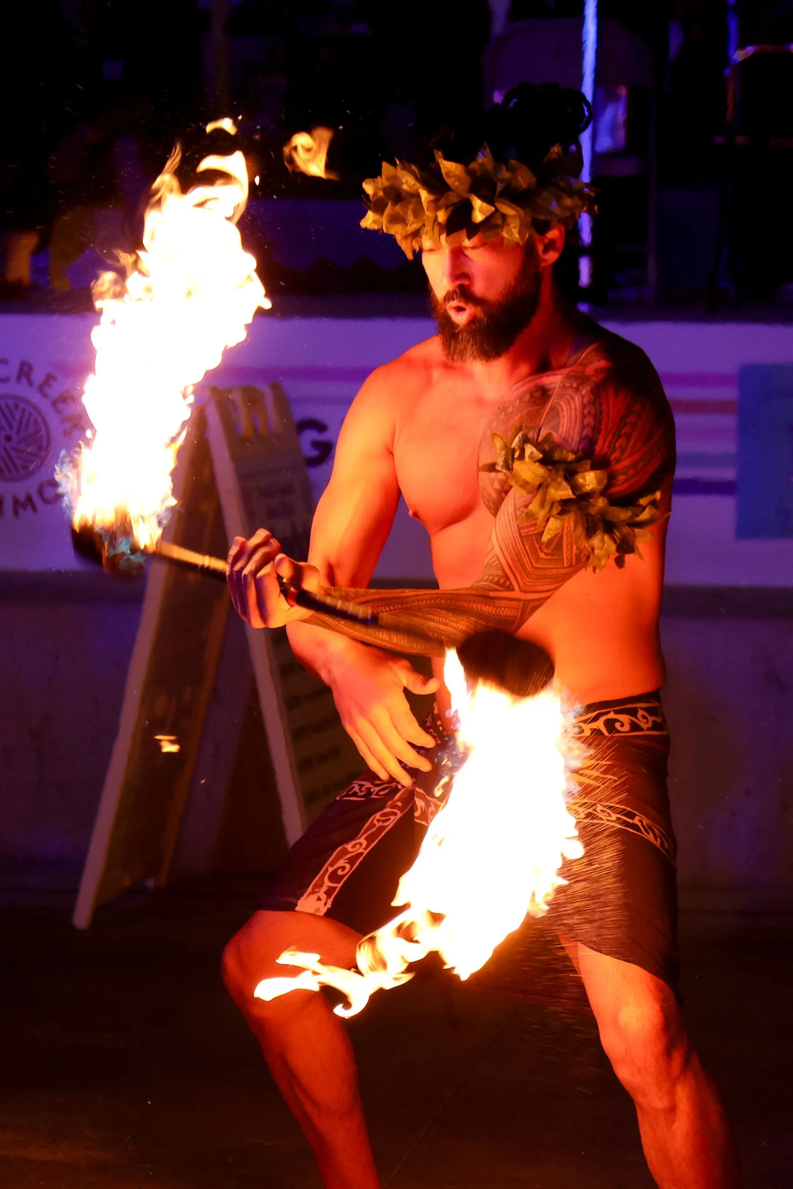 A shirtless man is holding a torch with flames coming out of it