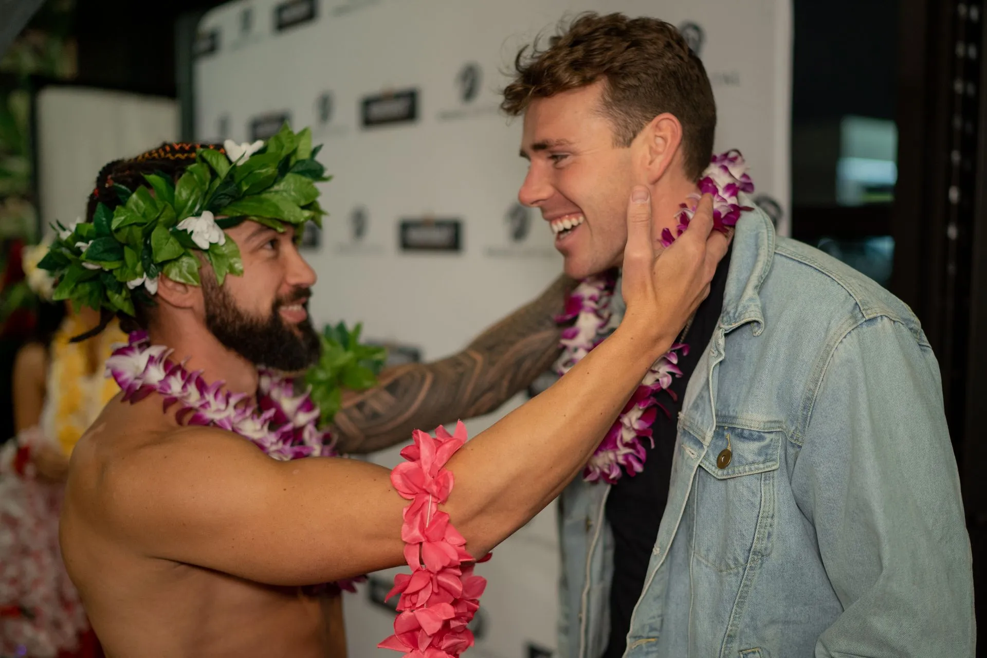 Two men are standing next to each other and one of them is wearing a lei.