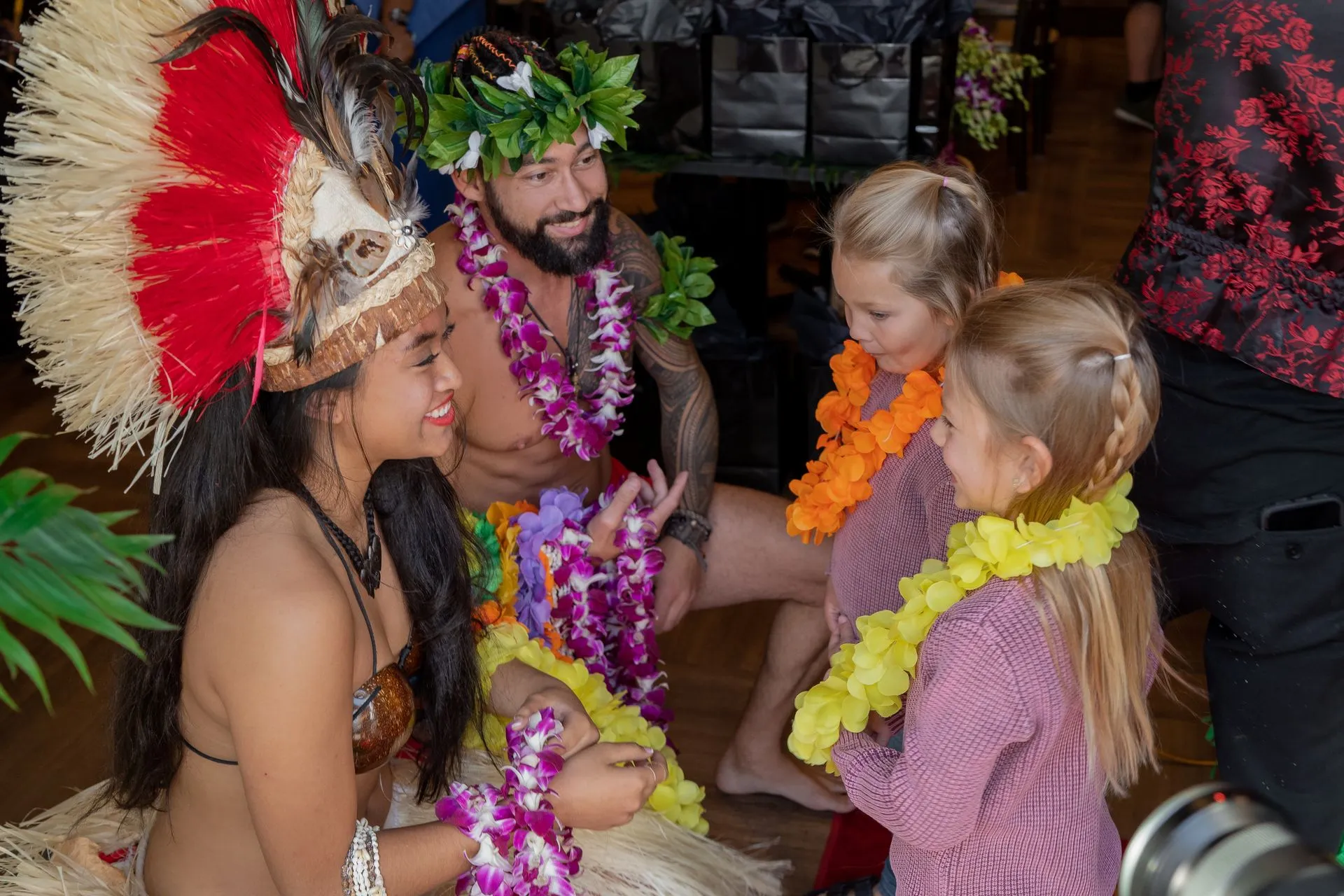 A group of people dressed in hawaiian costumes are standing next to each other.