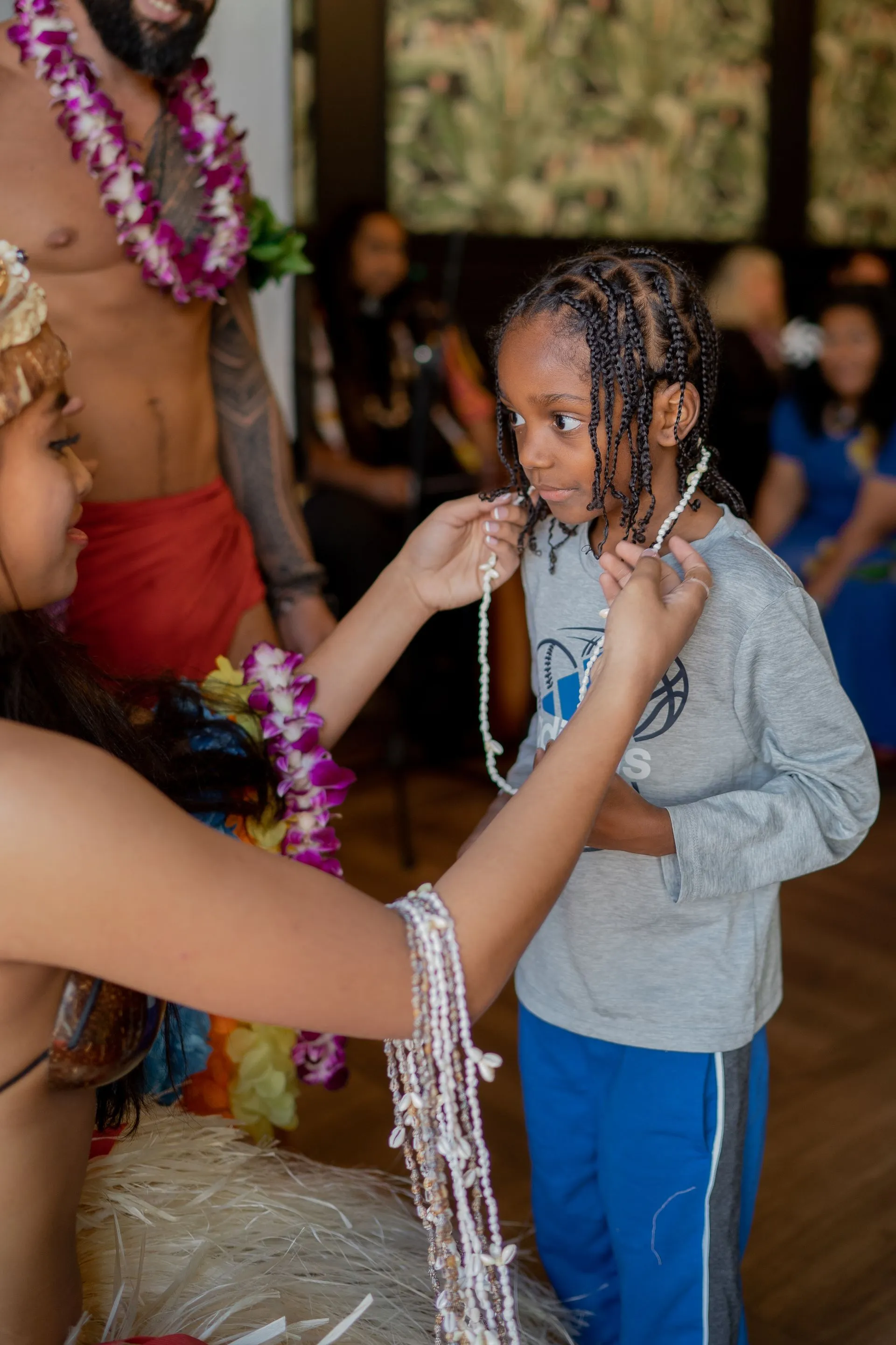 A woman is putting a necklace on a young boy.