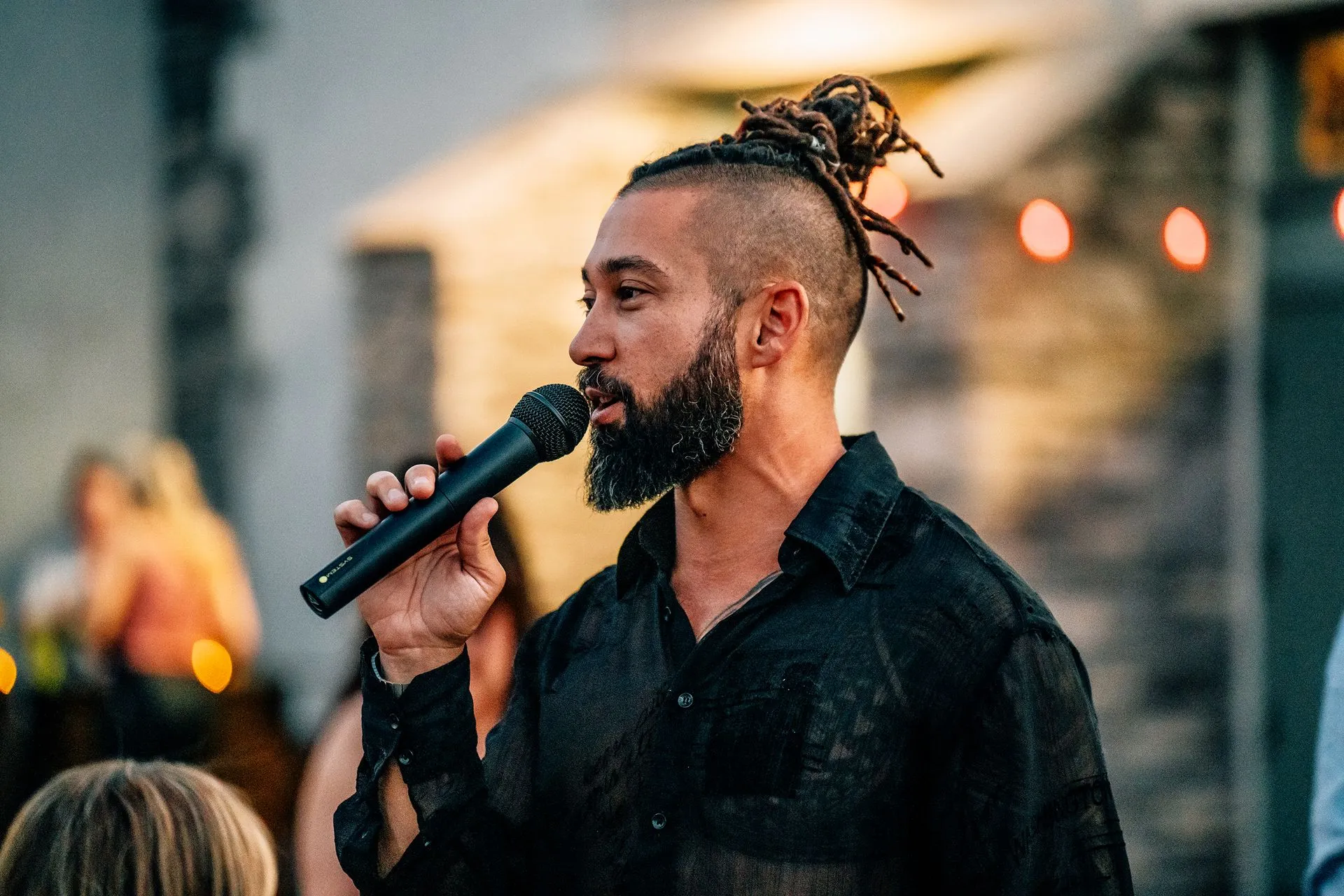 A man with dreadlocks is speaking into a microphone.