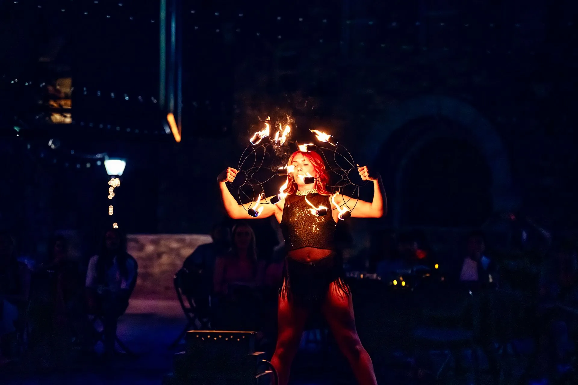 A woman is performing a fire show in the dark.