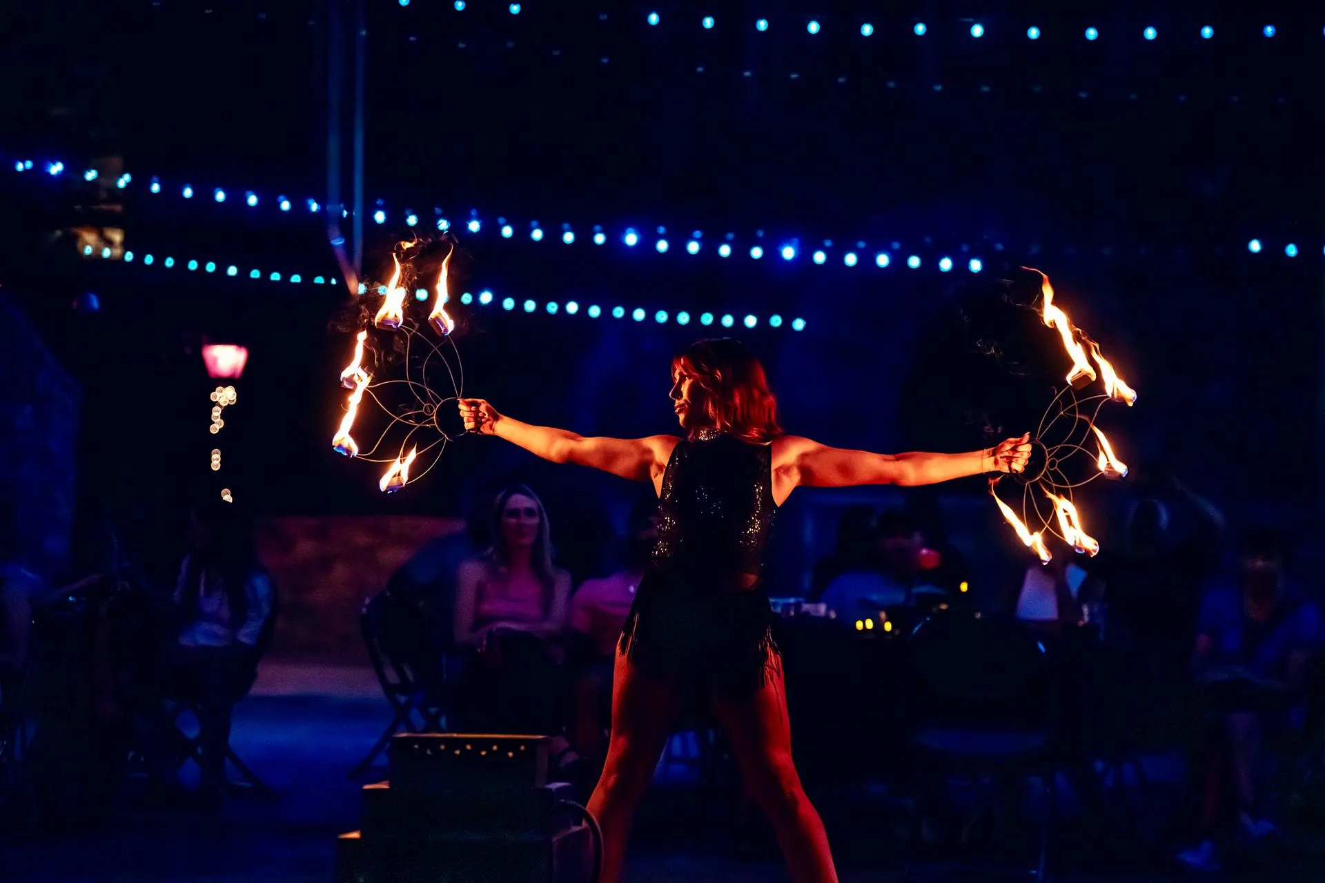 A woman is dancing with fire in her hands on a stage.