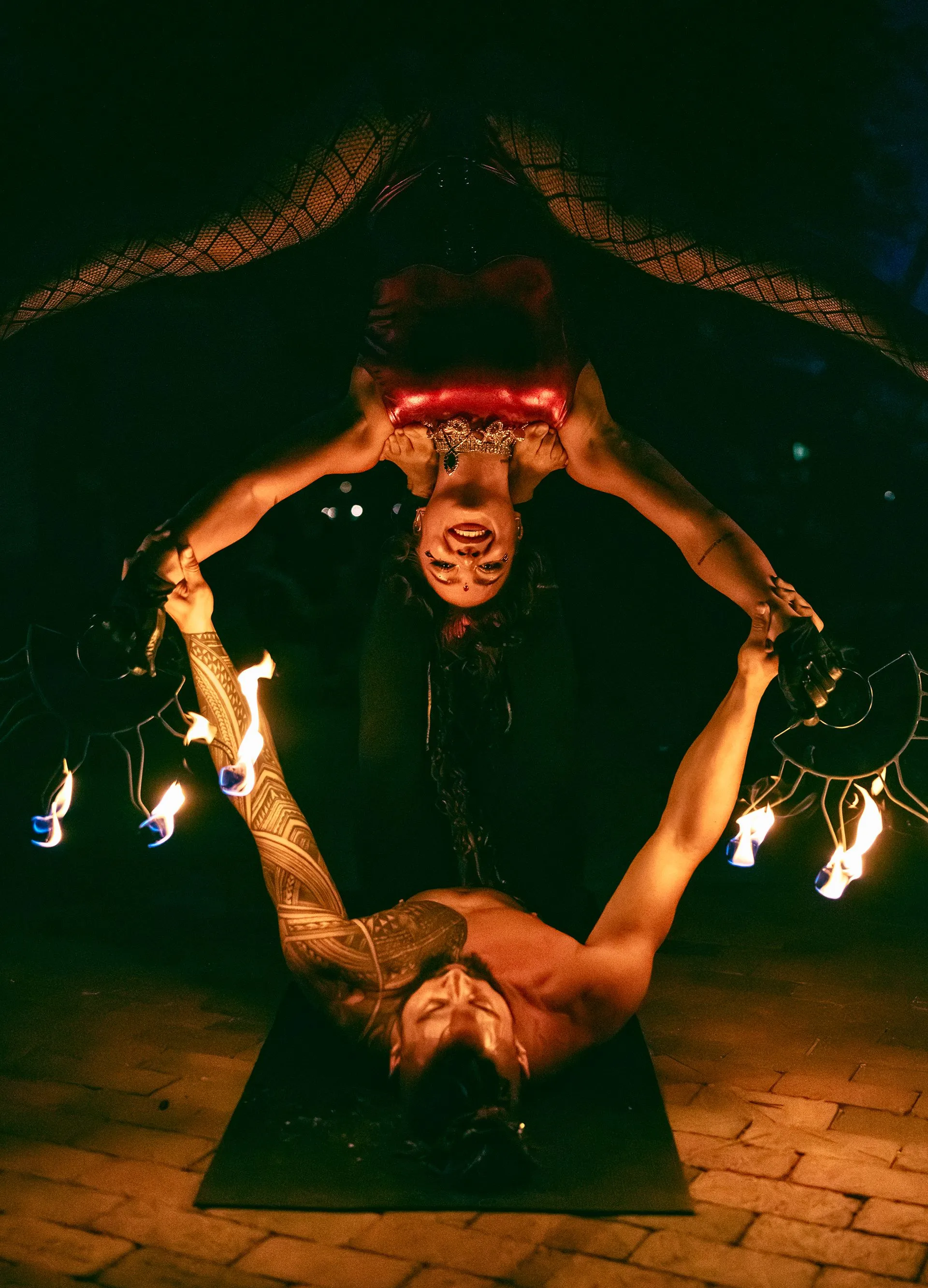 A man and a woman are doing a stunt with fire.