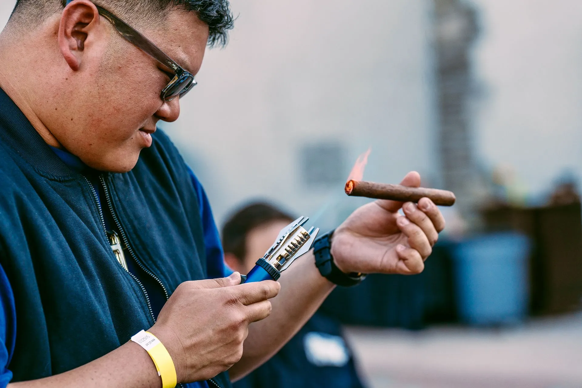 A man lighting a cigar with a torch.
