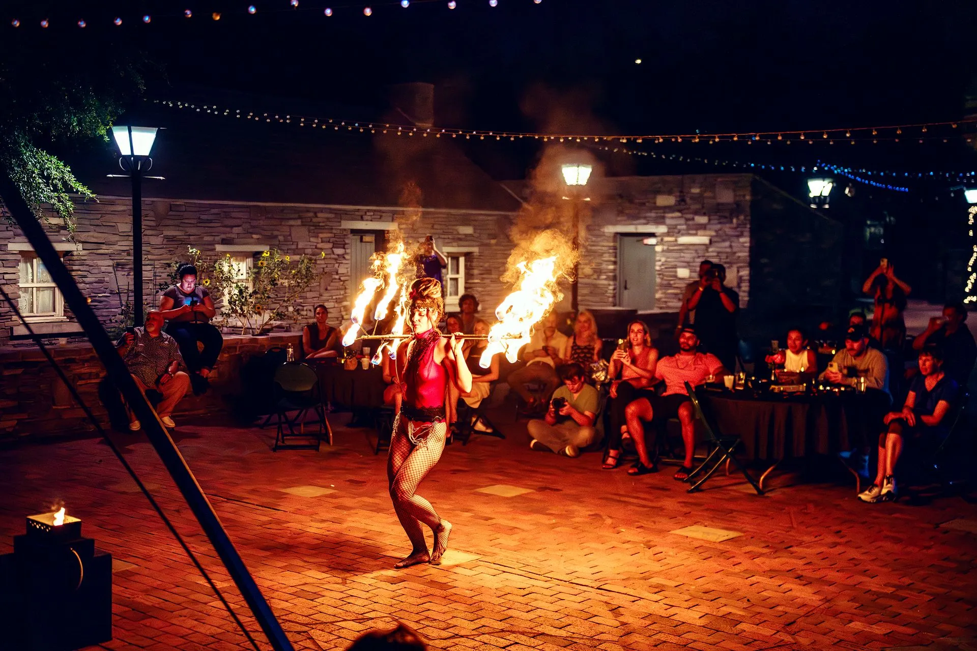 A woman is performing a fire show in front of a crowd of people.