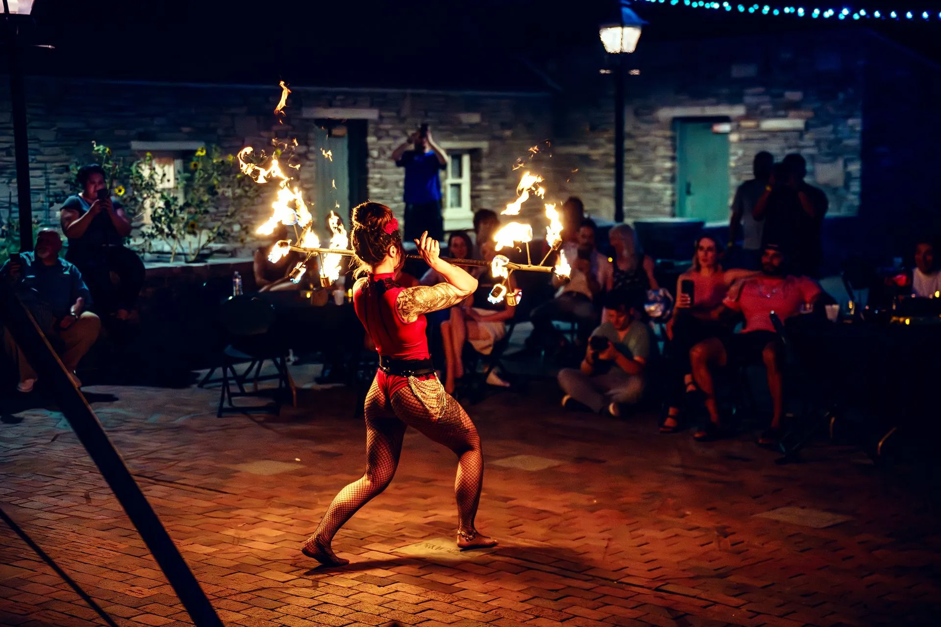 A woman is performing a fire show in front of a crowd of people.