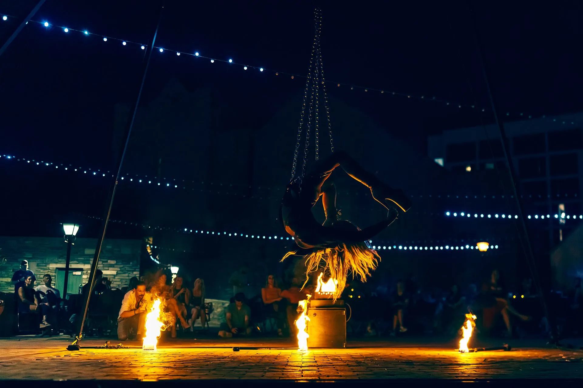 A group of people are sitting around a fire pit at night.