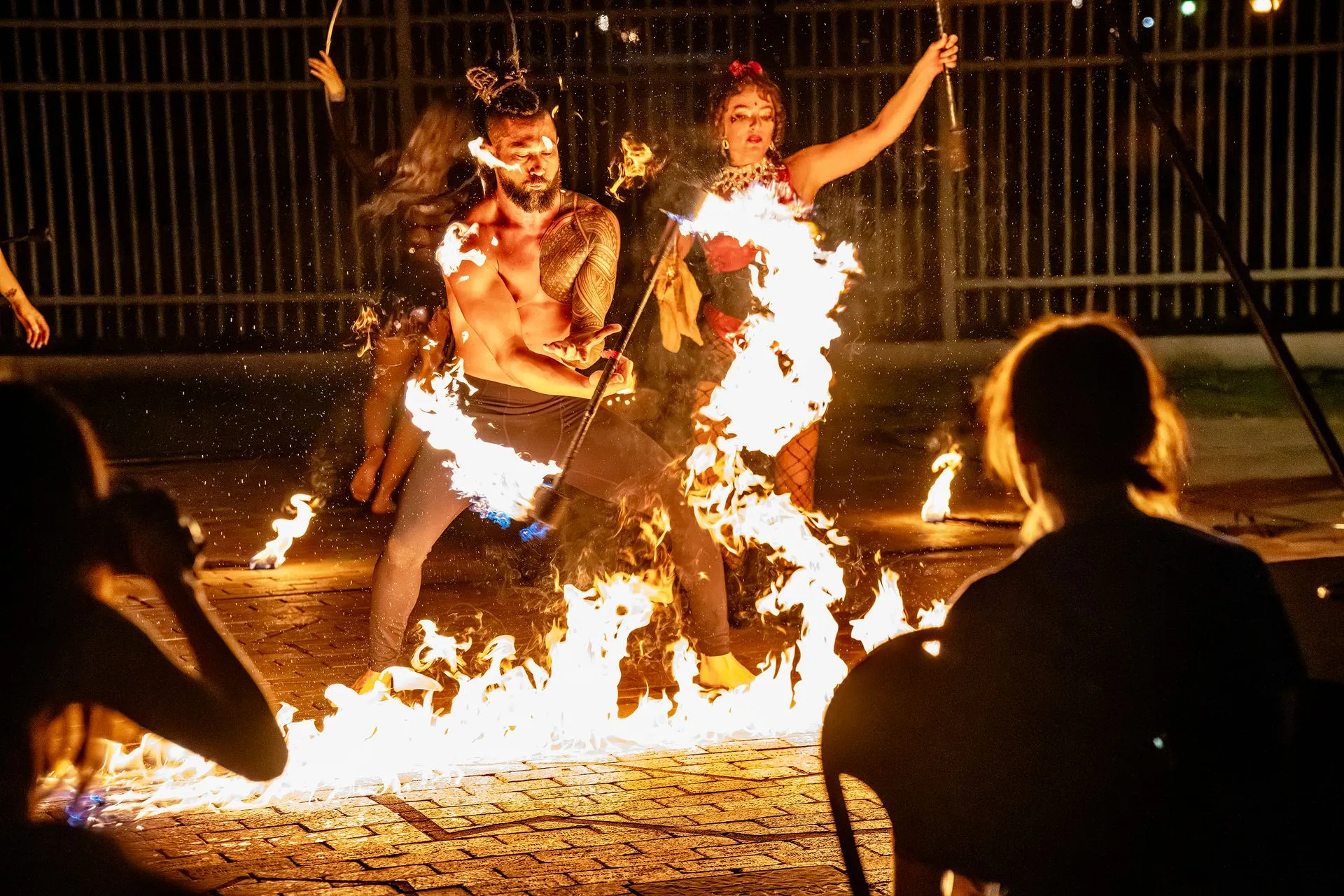 A man and a woman are dancing in front of a crowd while holding torches in their hands.