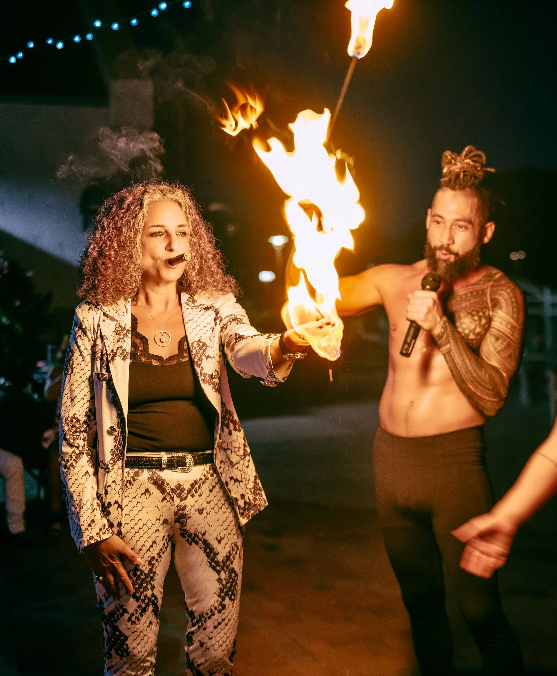 A man holding a microphone and a woman holding a fire torch