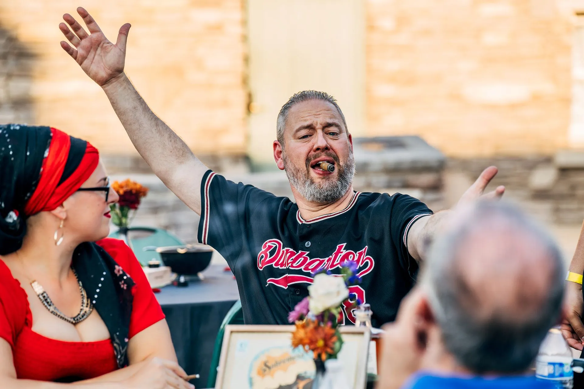 A man is sitting at a table with his arm in the air.