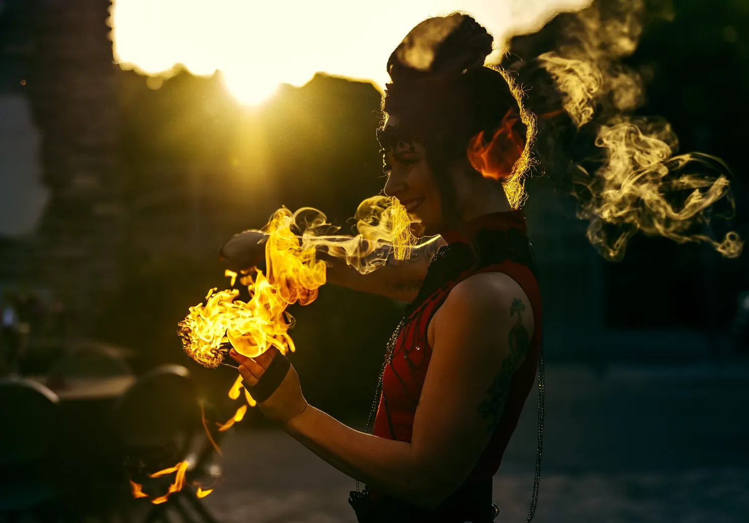 A woman in a red dress is blowing fire out of her mouth.