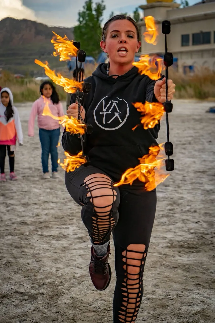 A woman is holding a torch with flames coming out of it.