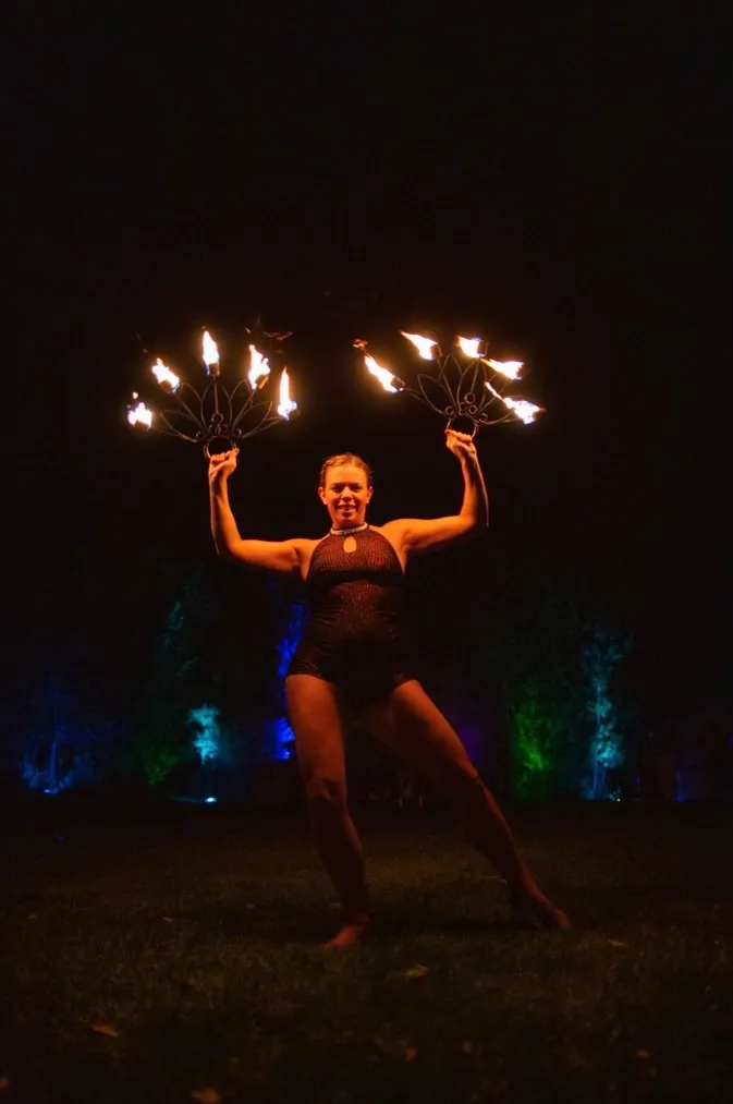 A woman is holding a bunch of fire sticks in the dark.