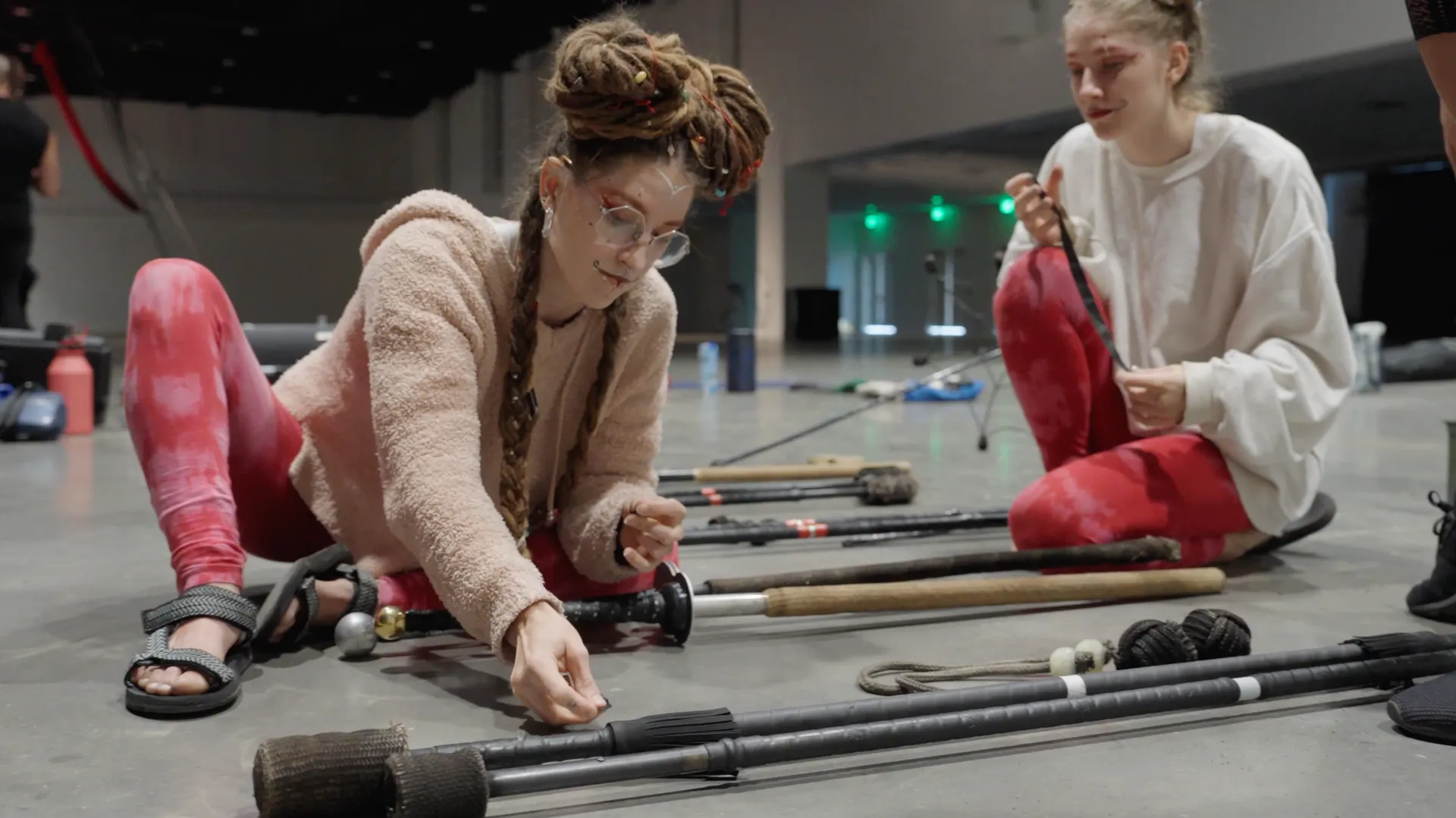 Two women are sitting on the floor playing with sticks.