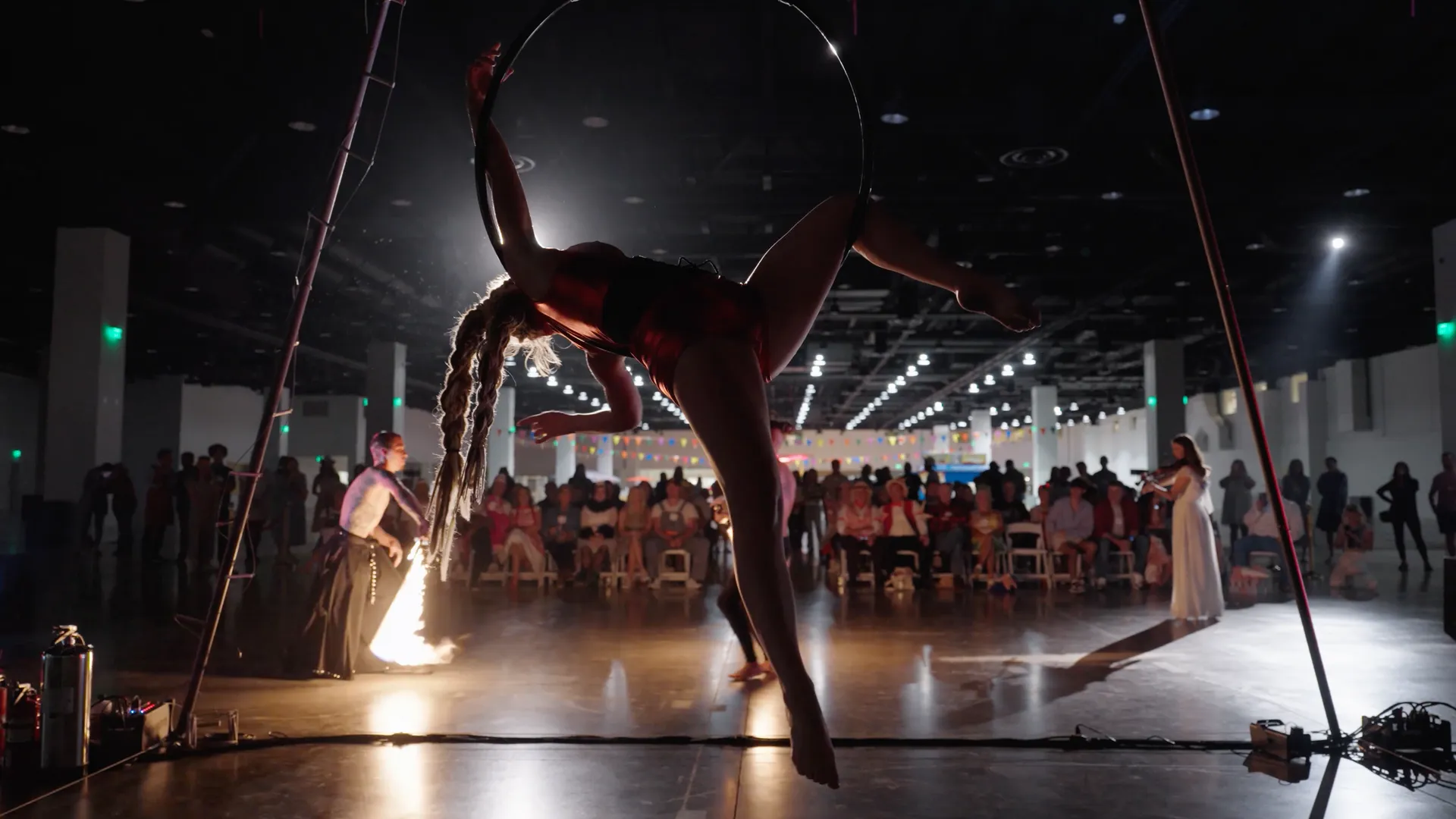 A woman is performing aerial acrobatics in front of a crowd.