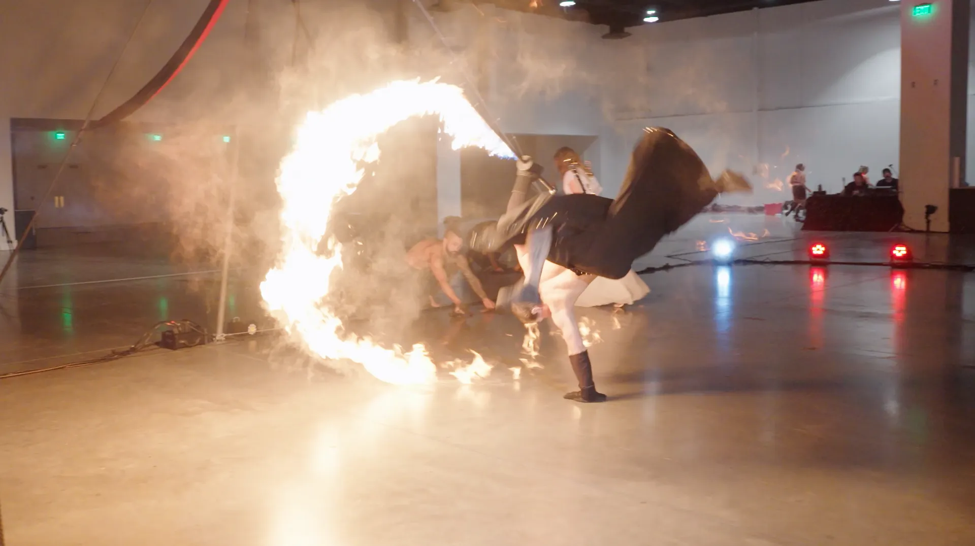 A group of people are performing a fire show in a large room.
