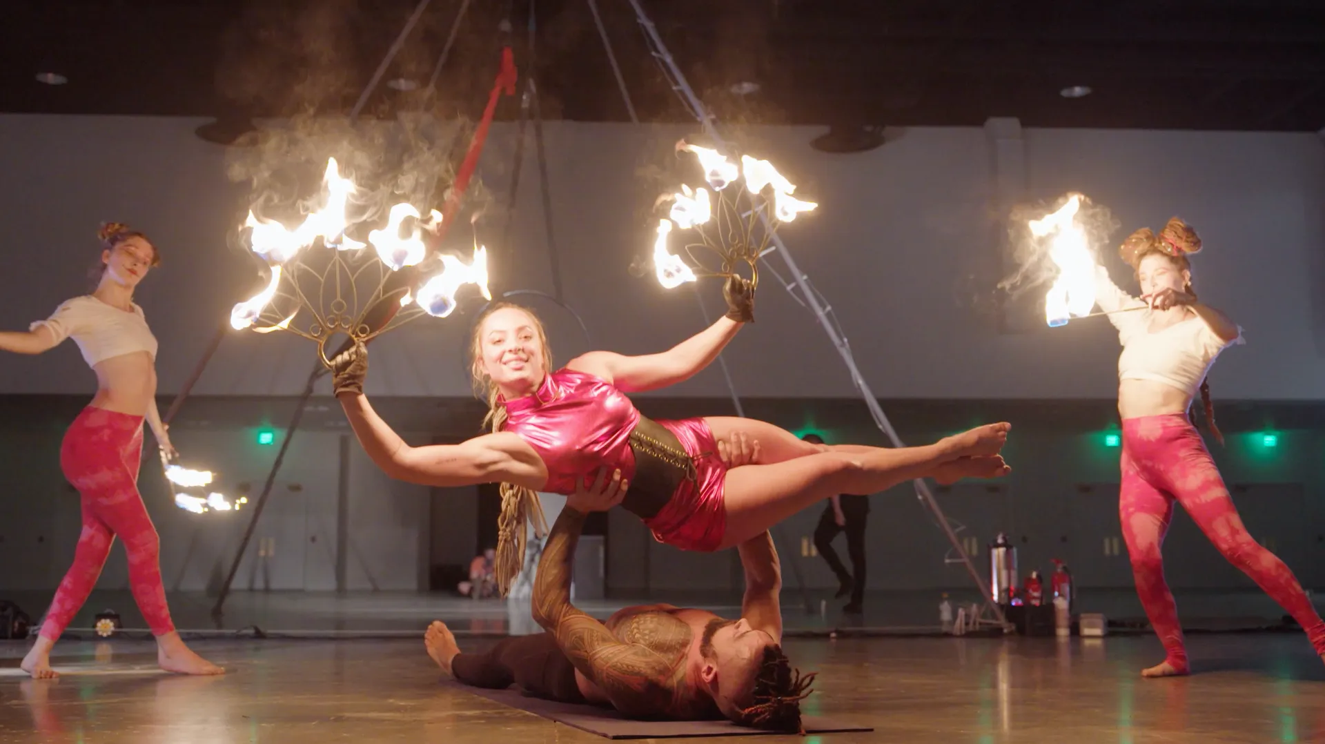 A group of people are performing aerial acrobatics with fire.