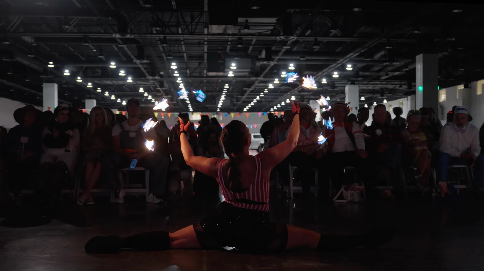 A woman is sitting on the floor with her legs crossed in front of a crowd of people.