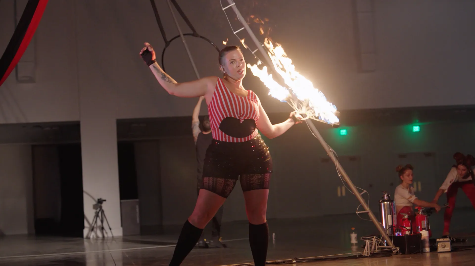 A woman is holding a stick with fire coming out of it.