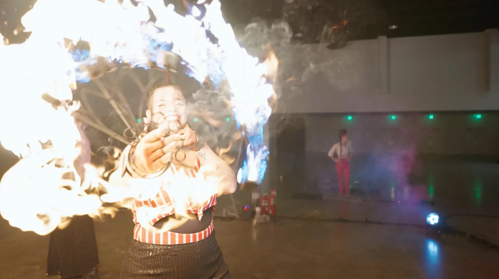 A woman is holding a fan of fire in her hand.