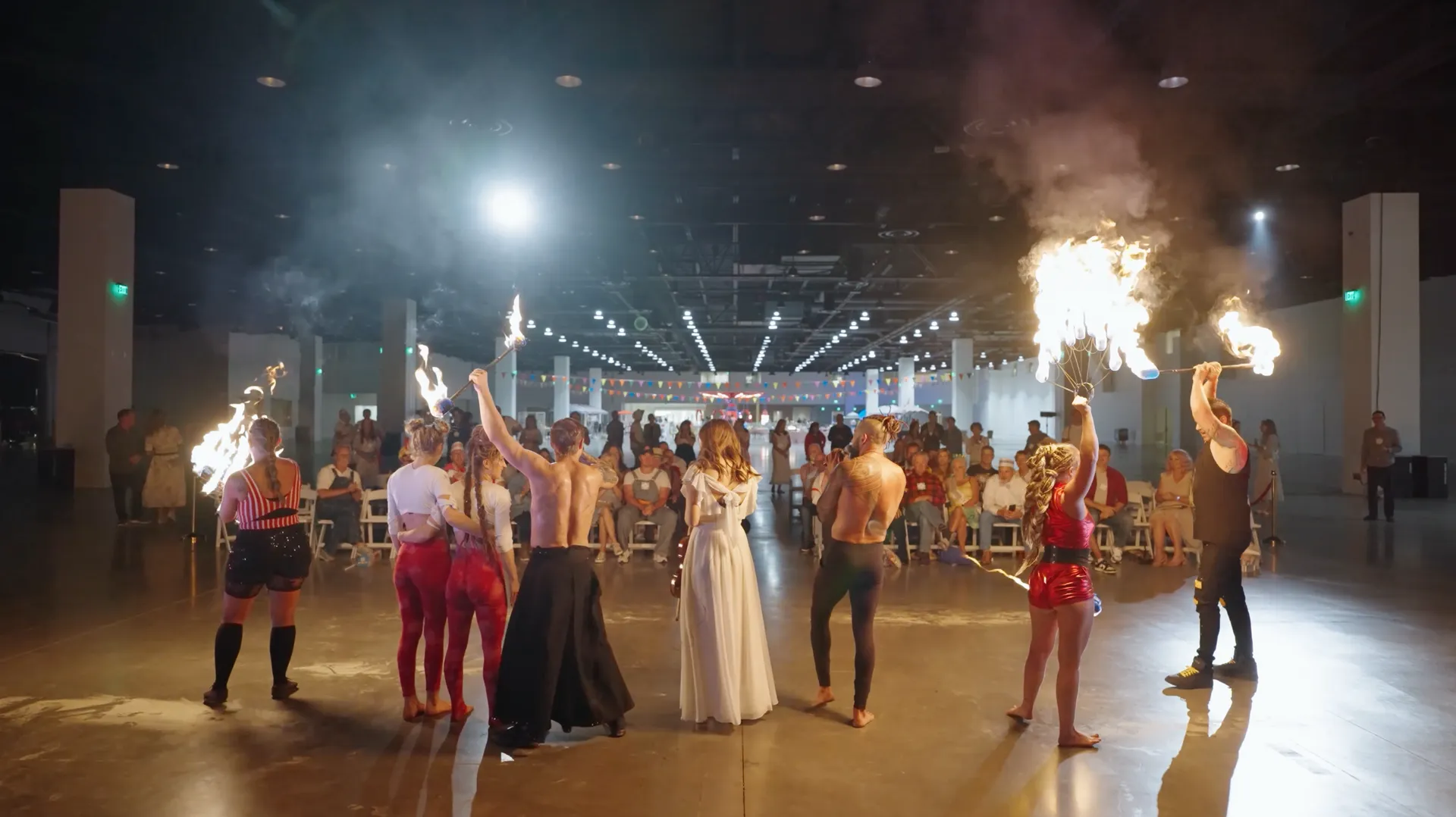 A group of people are holding fireworks in their hands in a large room.