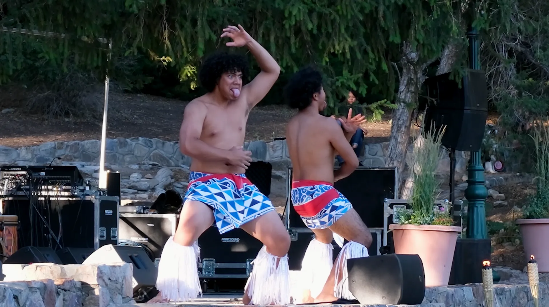 Two shirtless men are dancing in front of a stage