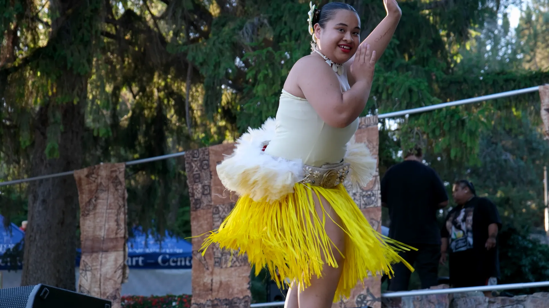 A woman in a white dress and yellow skirt is dancing.