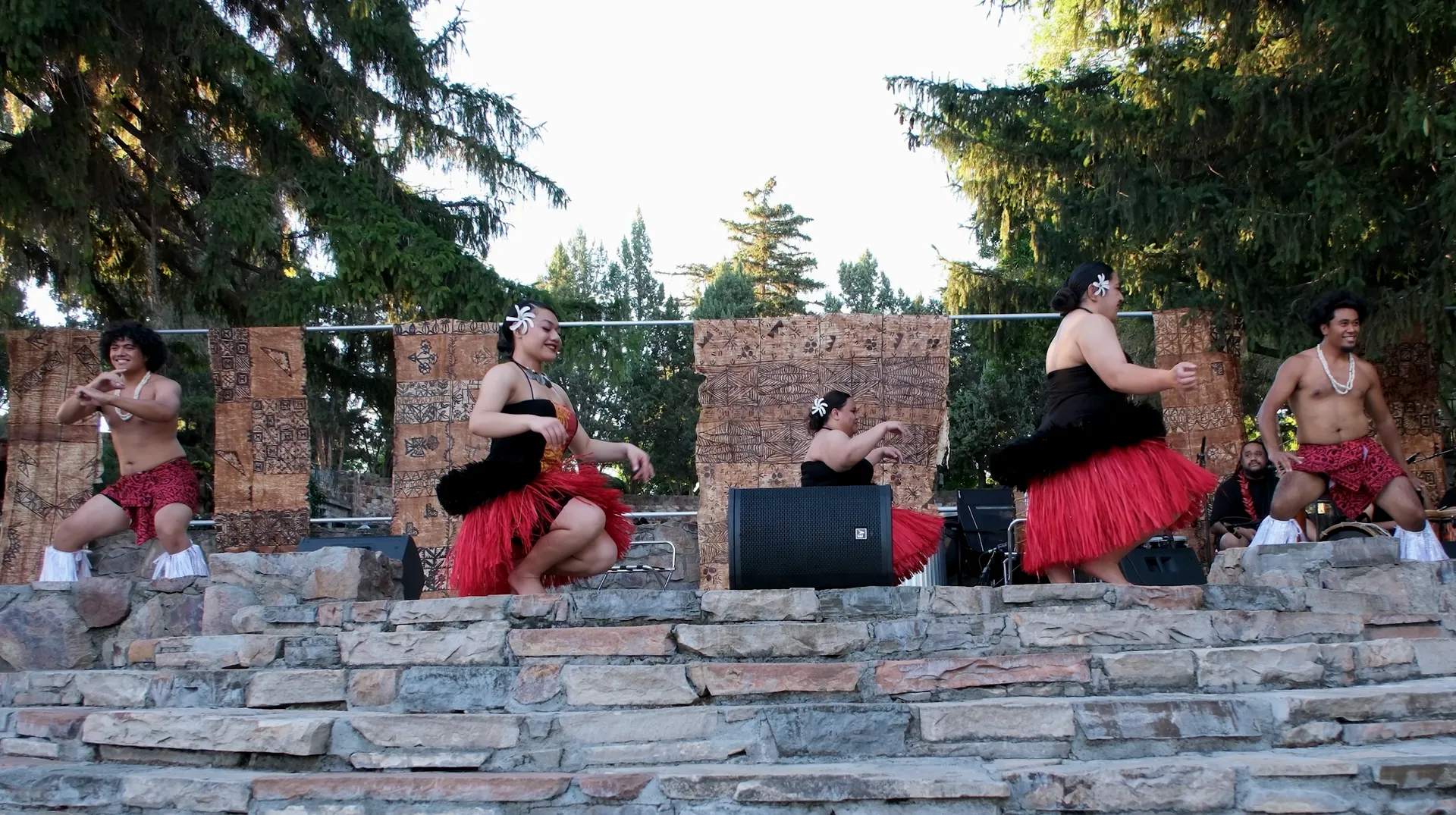 A group of people are dancing in front of a stone wall