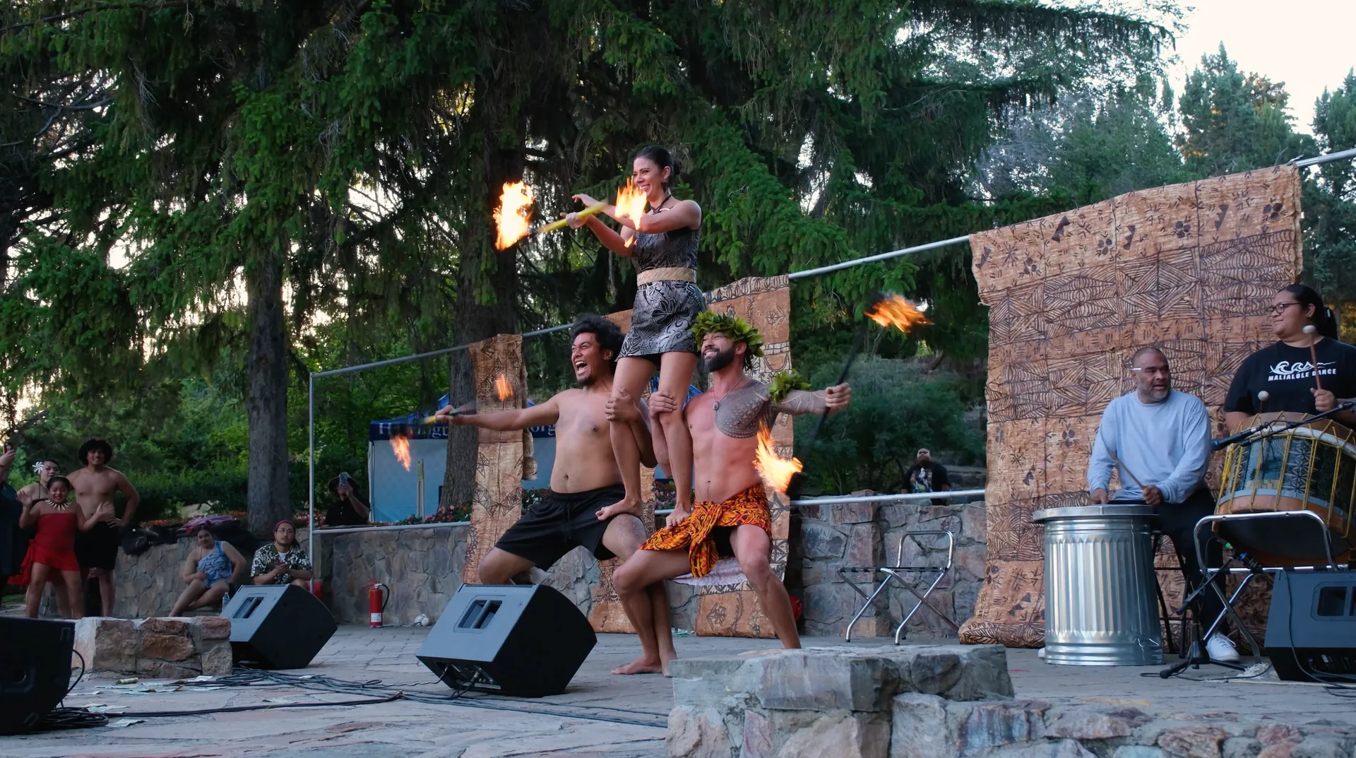 Three performers stacked on top of each other spinning fire.