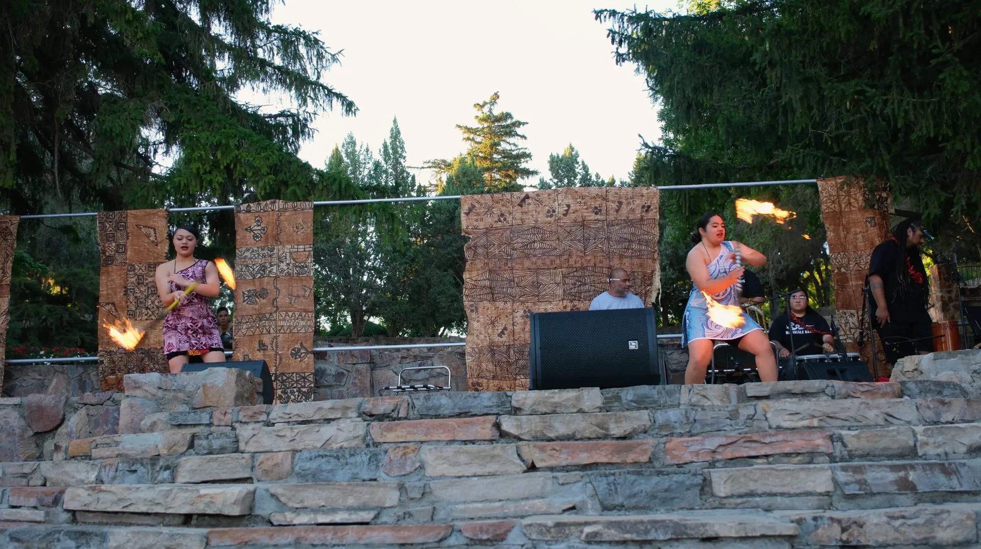A woman is holding a fire torch while standing on a stone stage.