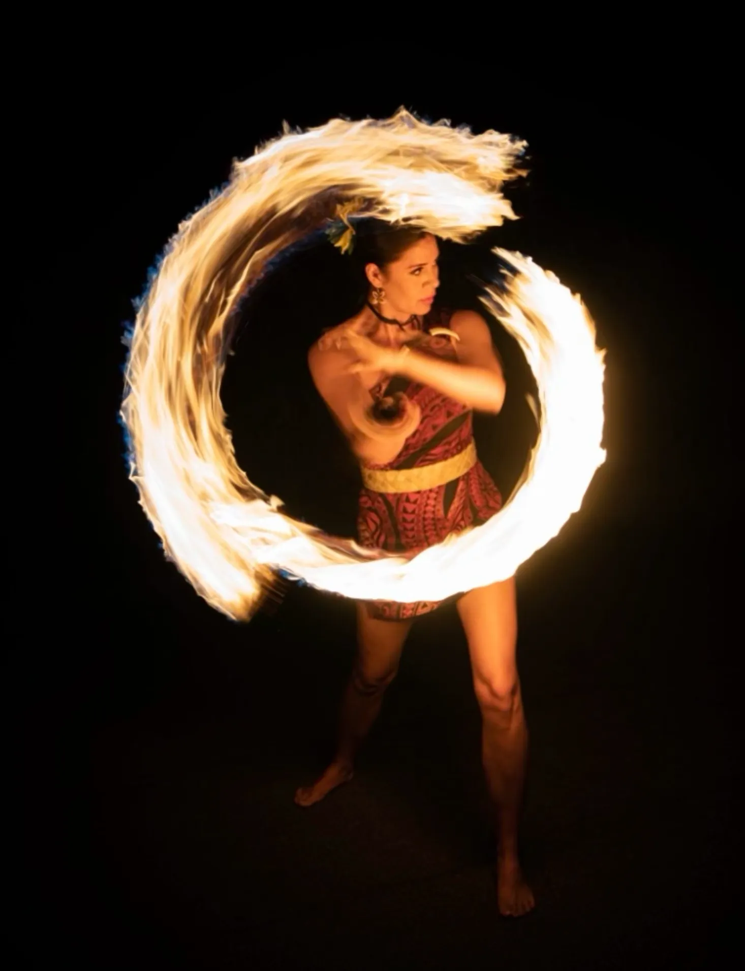 A woman is spinning a circle of fire in the dark.
